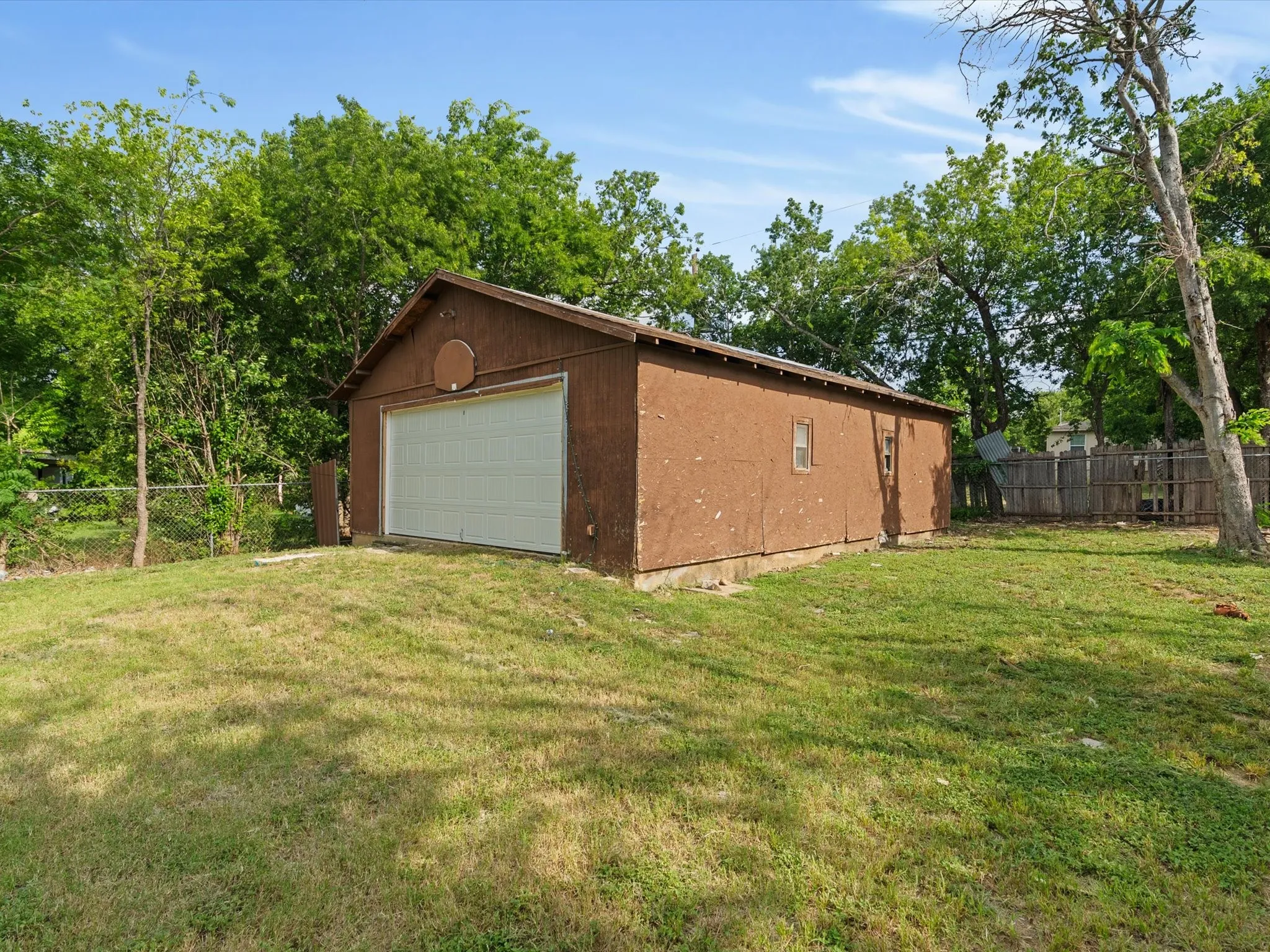 Detached garage with a paneled overhead door, wood-paneled siding, and a single window