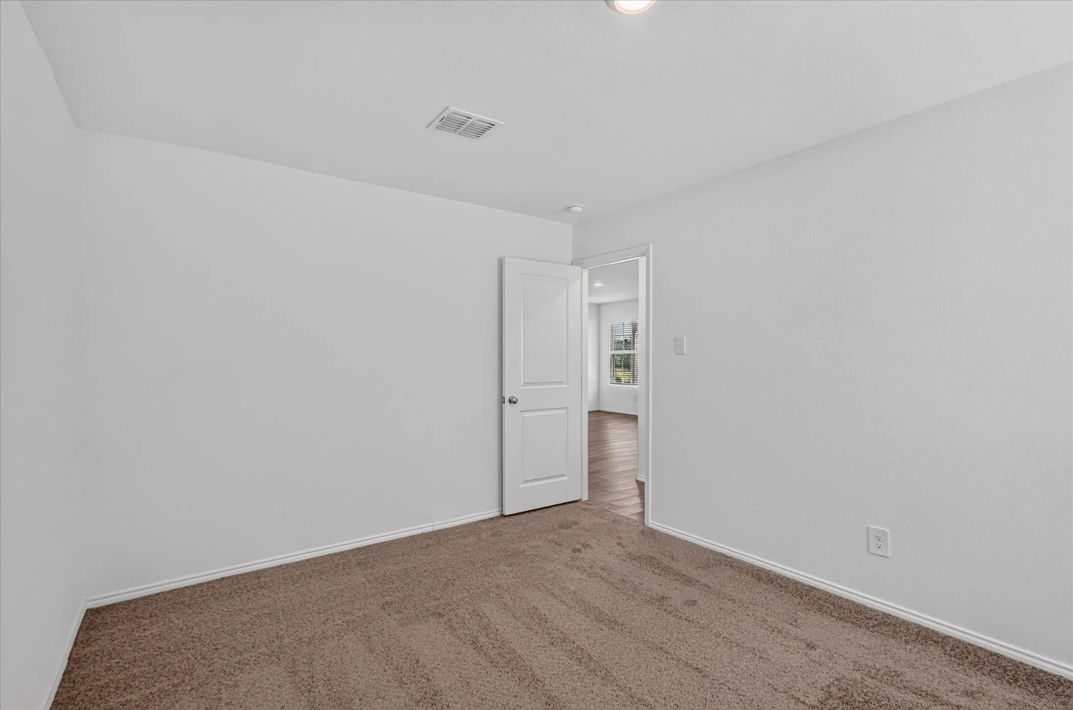 Carpeted room with white walls, a white door, and a flush-mount ceiling light