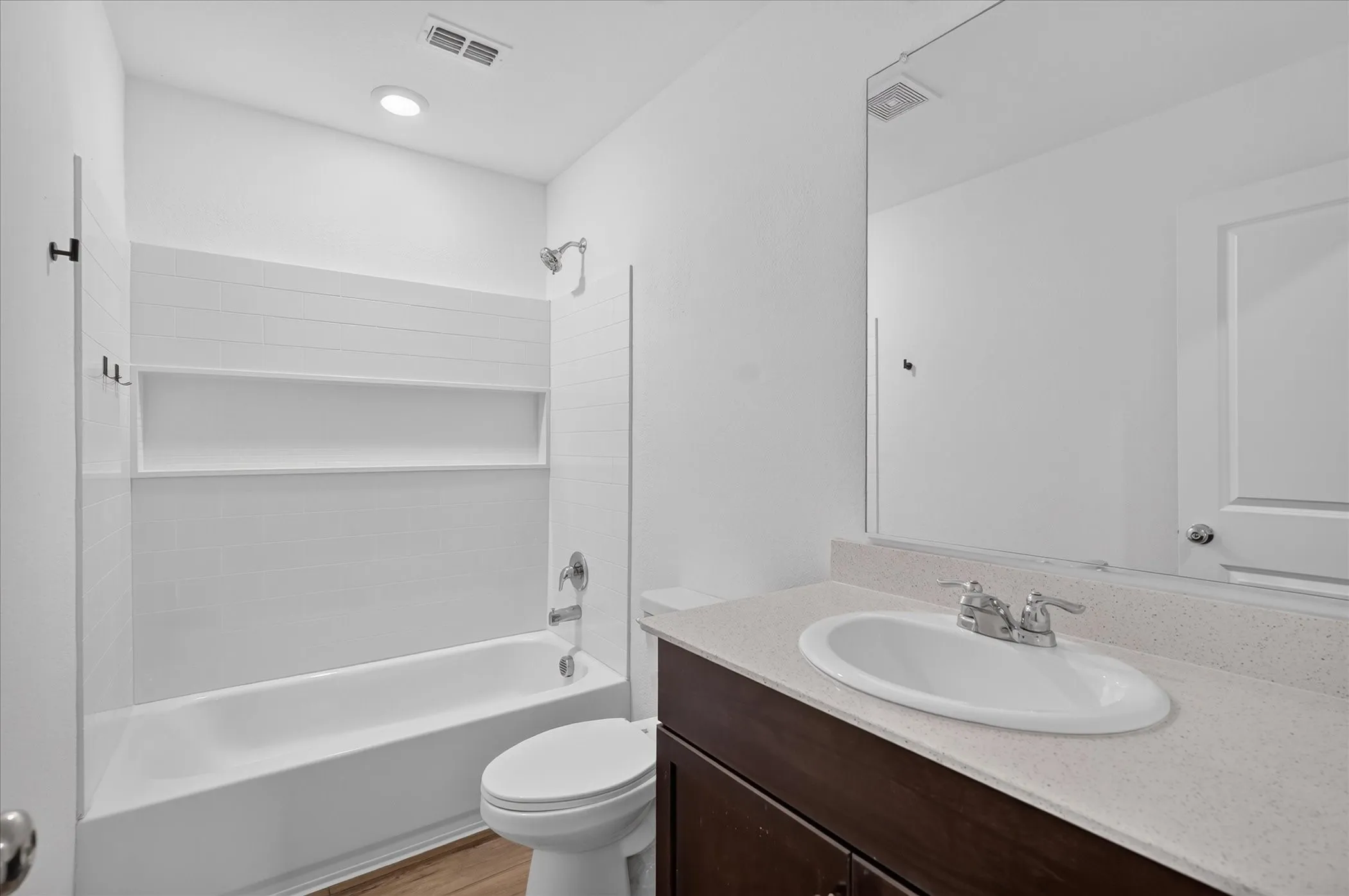 Bathtub with subway tile surround, integrated shelf, and chrome fixtures