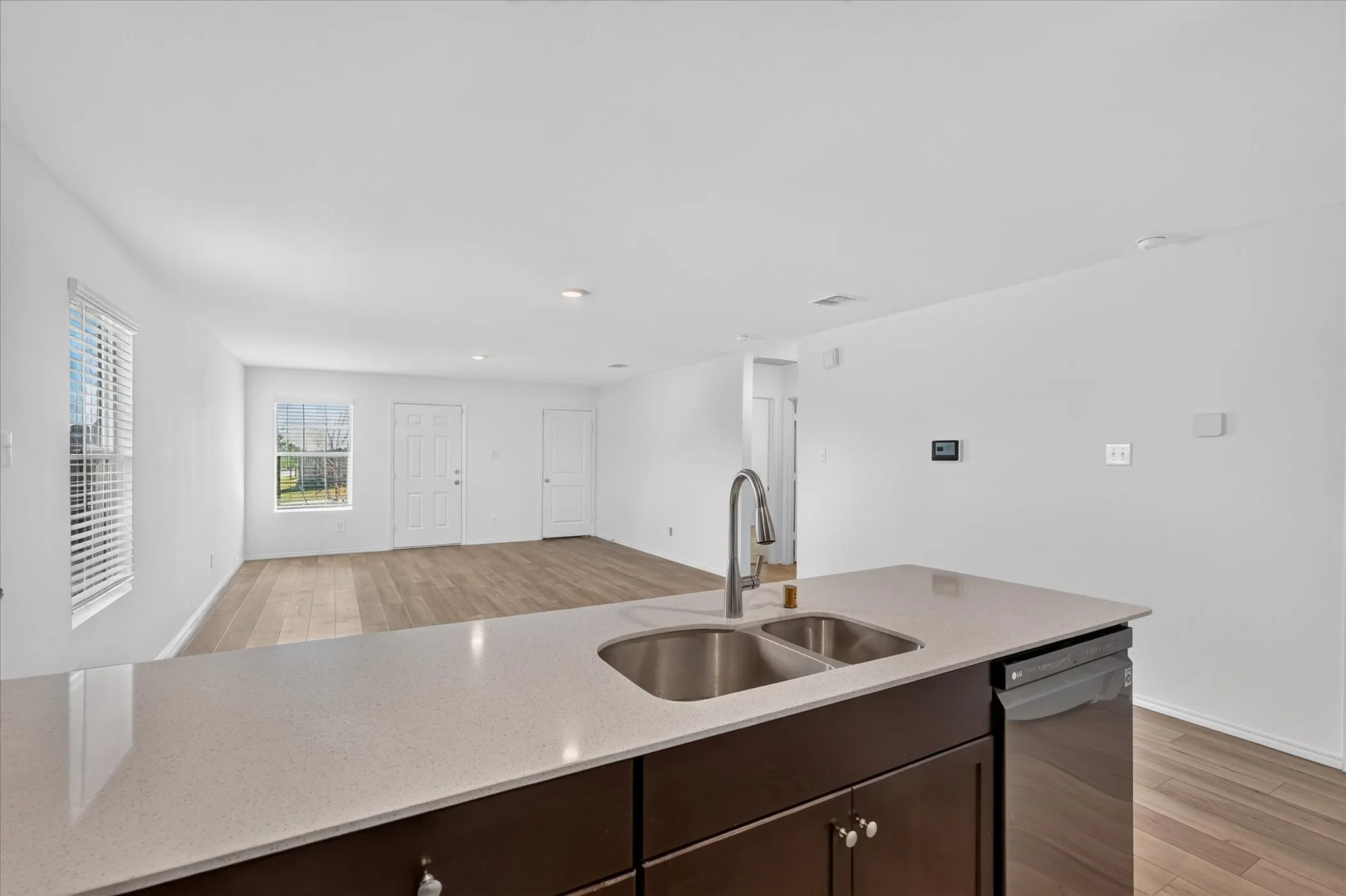 Kitchen island with a double stainless steel sink, gooseneck faucet, and light-toned countertop