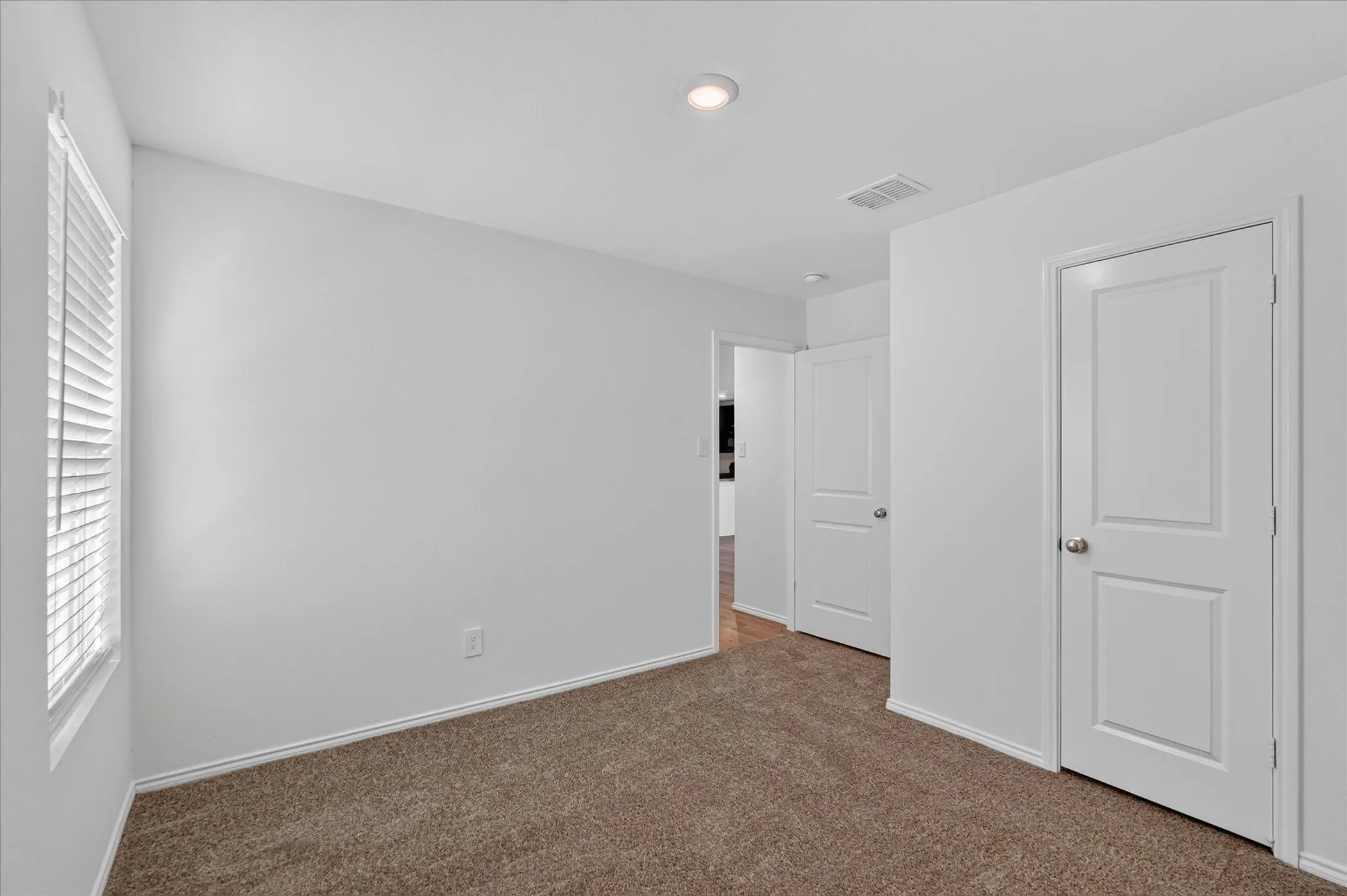 Carpeted room featuring a white interior door, a window with horizontal blinds, and a recessed ceiling light