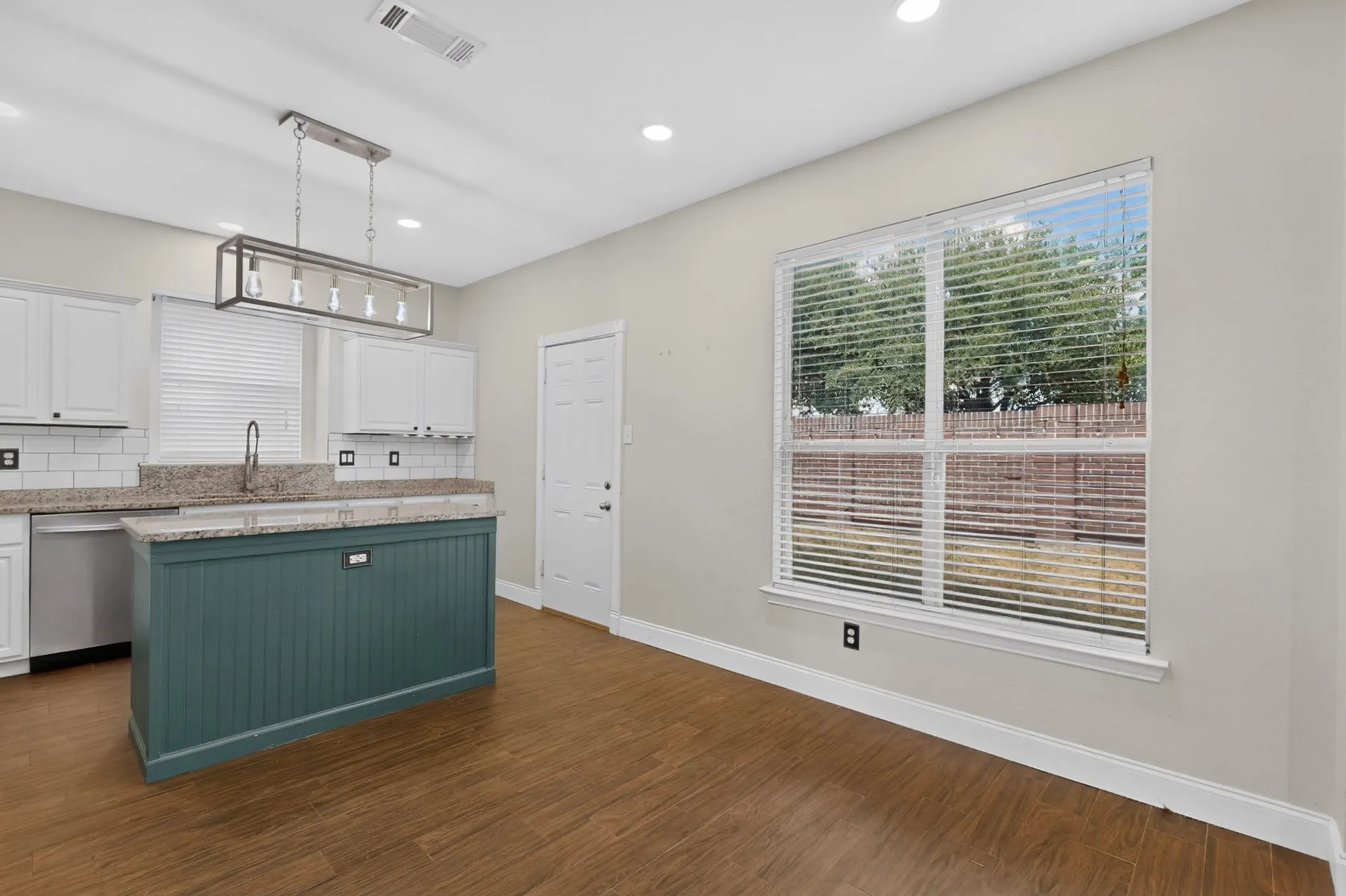 Kitchen featuring a central island with beadboard paneling, stone countertops, white shaker cabinetry, and a subway tile backsplash