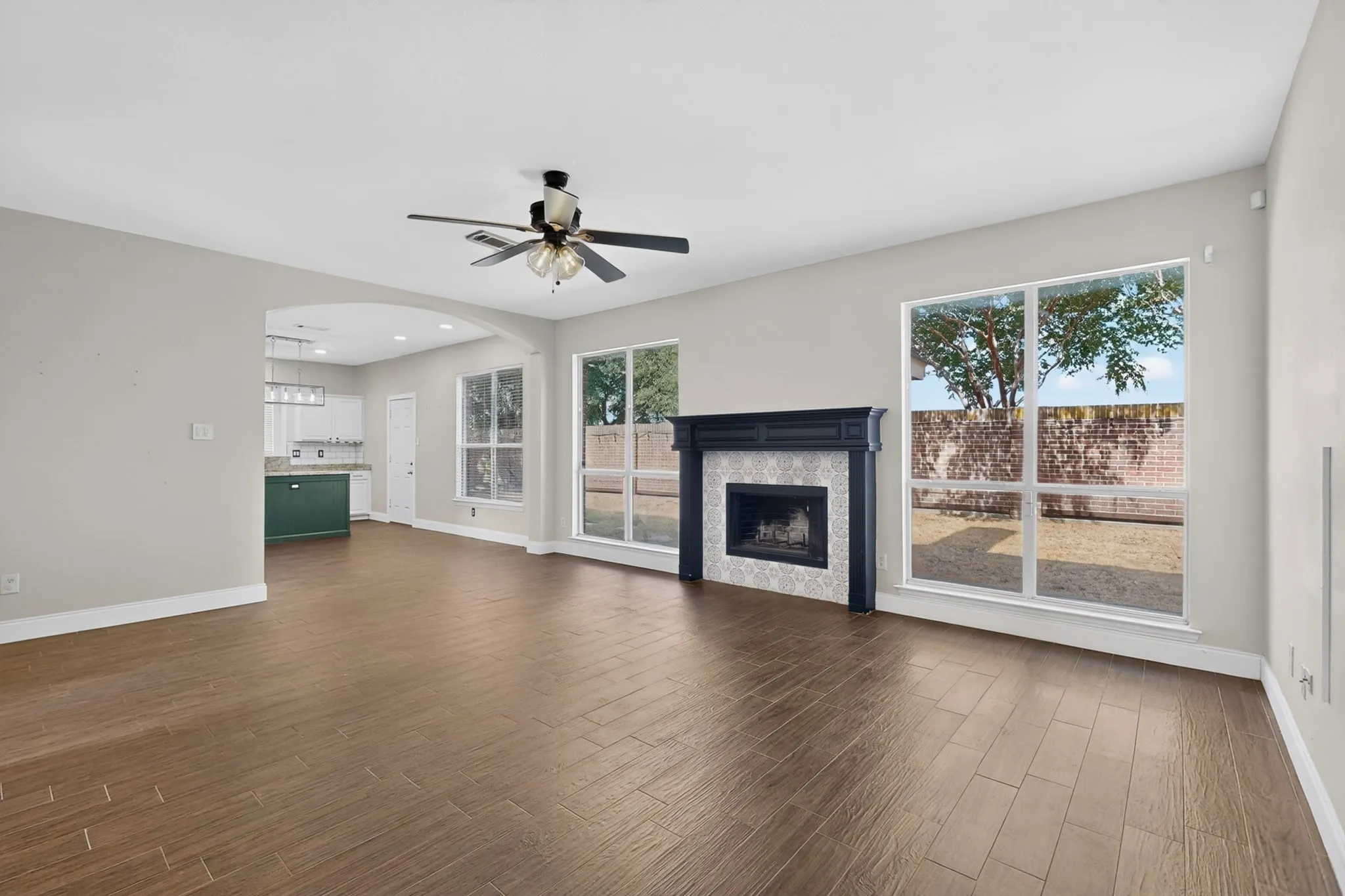 Wood-finish flooring throughout, featuring a fireplace with a decorative tile surround and dark mantel