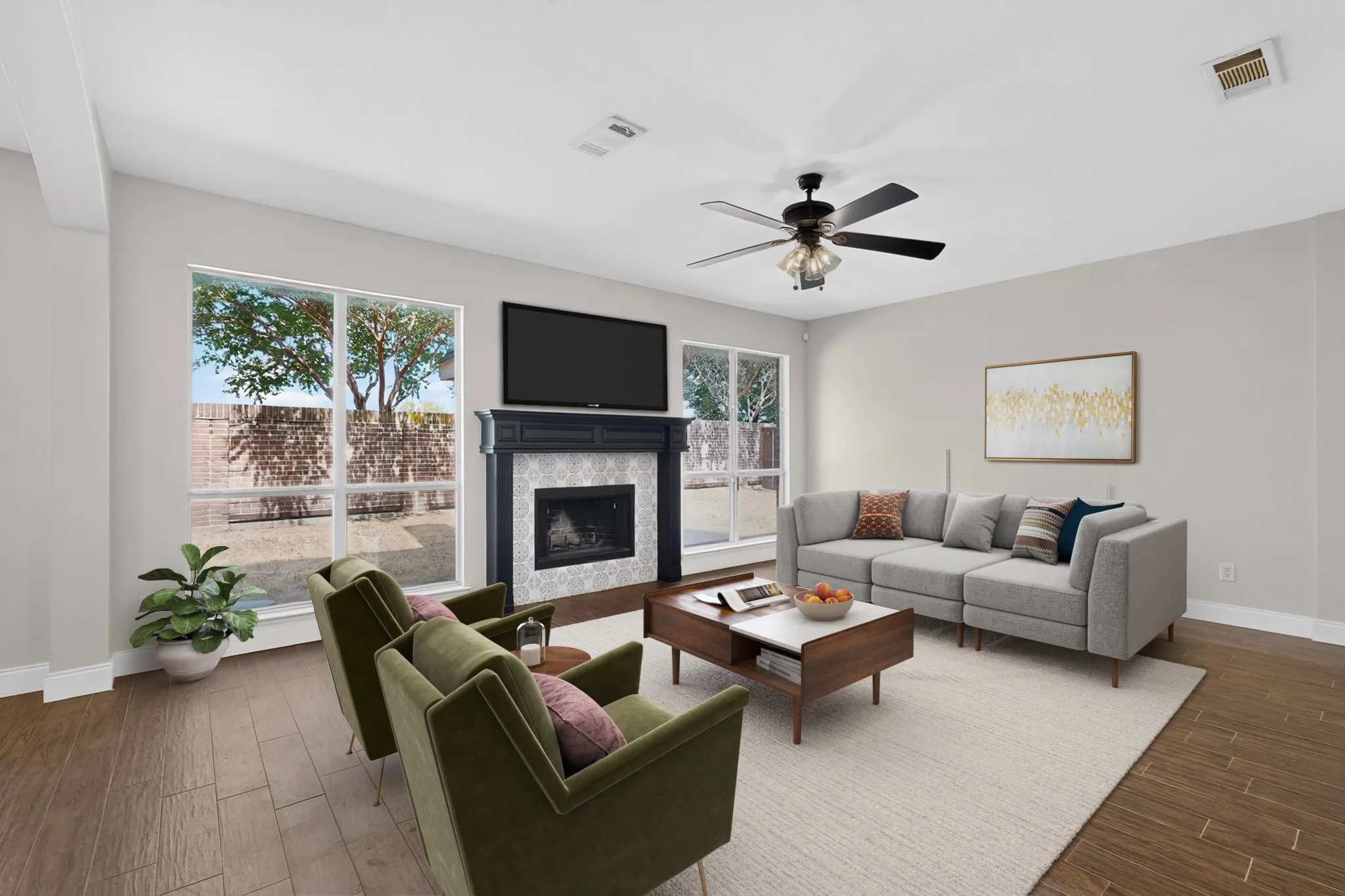 Wood-finish flooring, a ceiling fan with integrated lighting, multiple windows, a built-in fireplace with a decorative mantel, and light-colored wall paint. This photo has been virtually staged.
