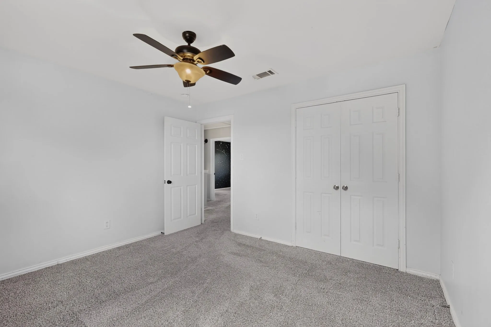 Textured carpeting, white painted walls, and a ceiling fan with integrated lighting