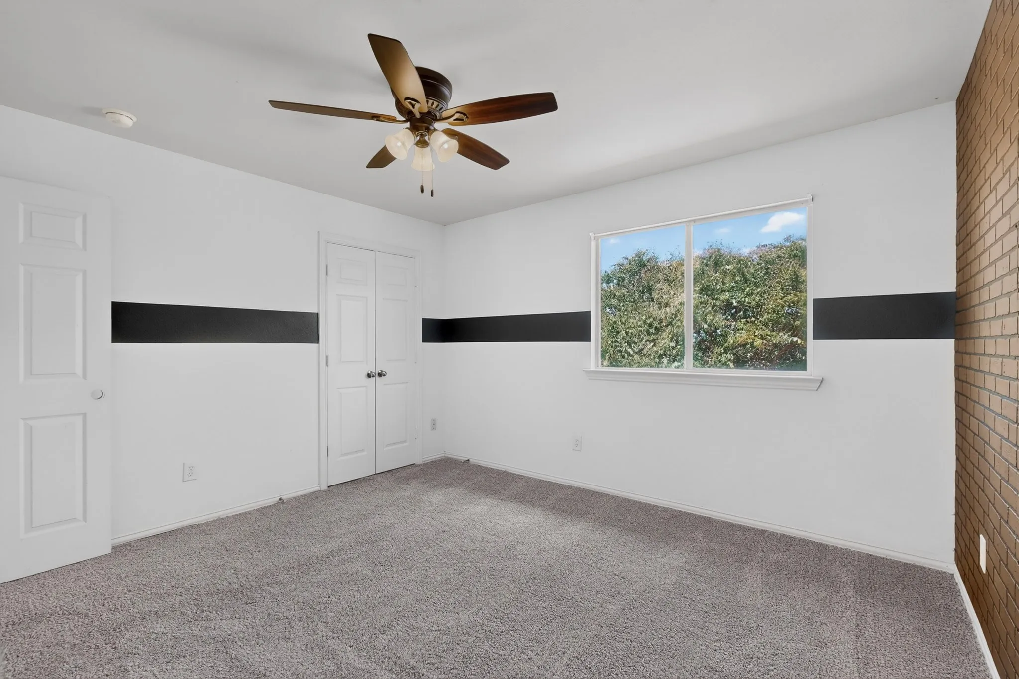 Room with light gray carpet, a white ceiling with a ceiling fan, and two white doors