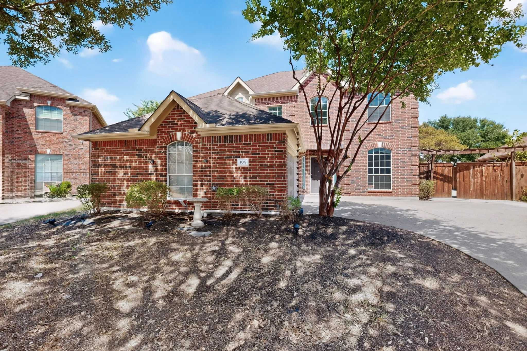 Brick exterior with arched windows, gabled rooflines, and a paved driveway