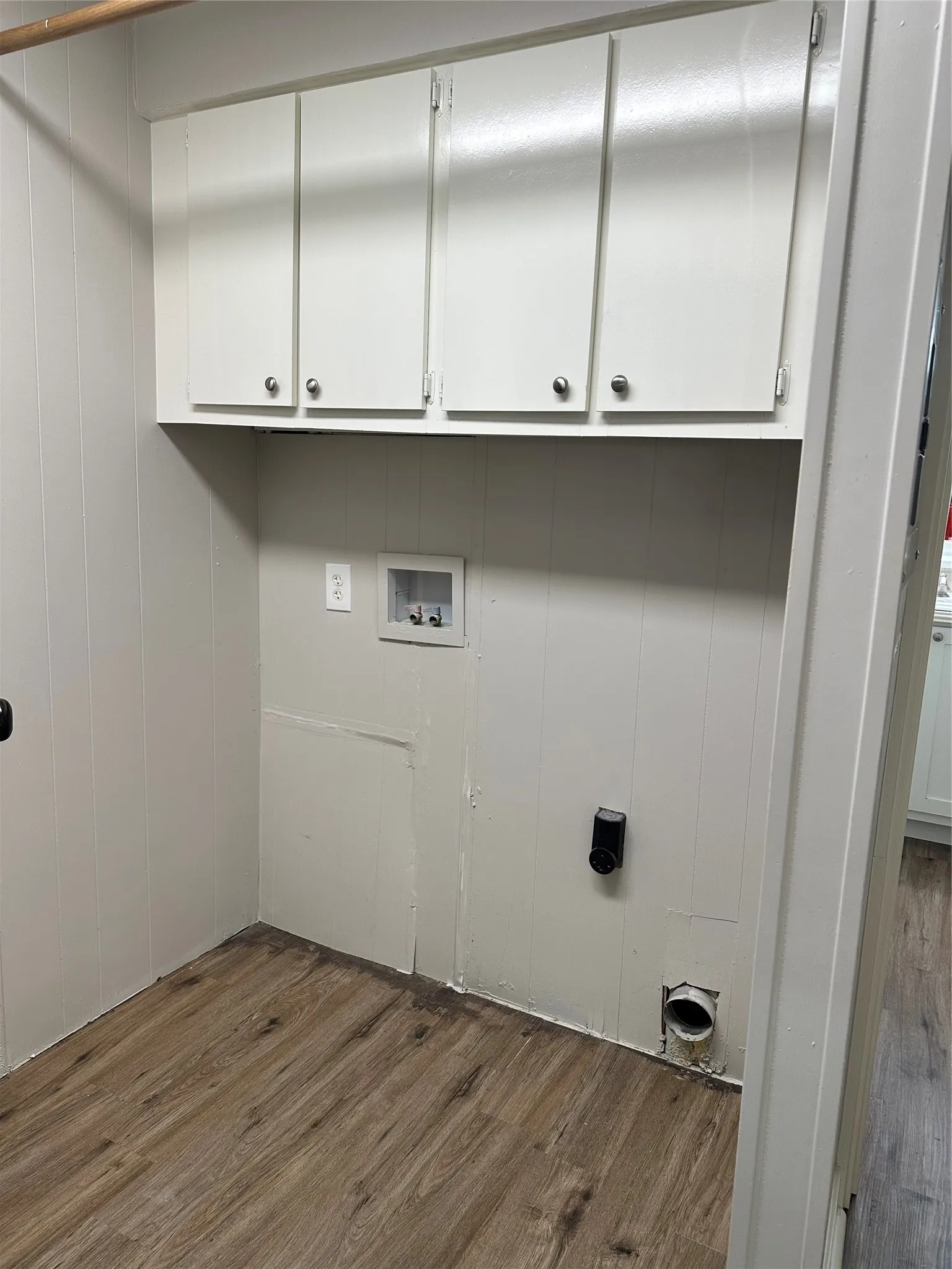 Laundry room with wood finished floors, cabinet space, and washer hookup