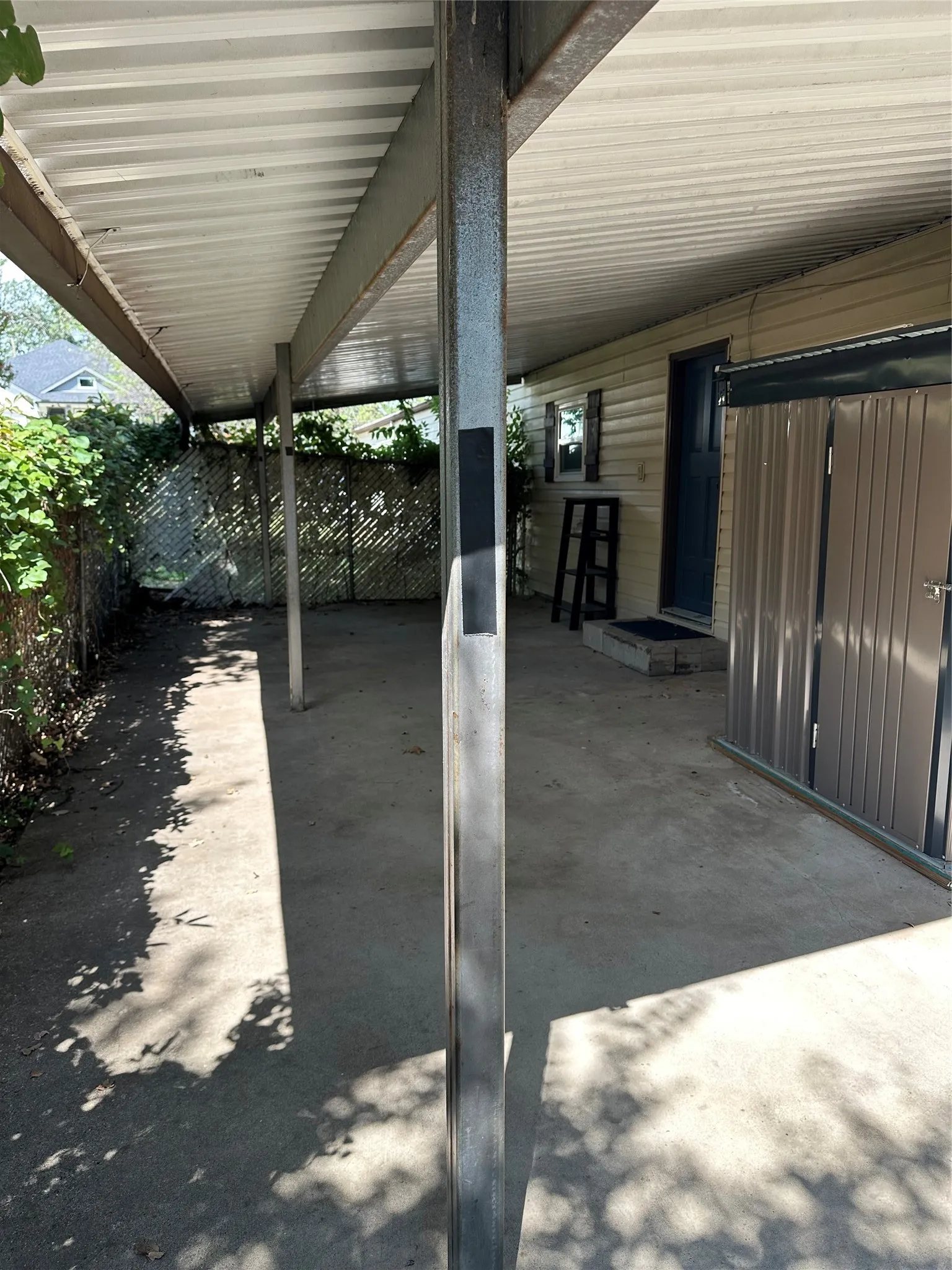 Large, fenced private back covered patio and metal storage closet on right