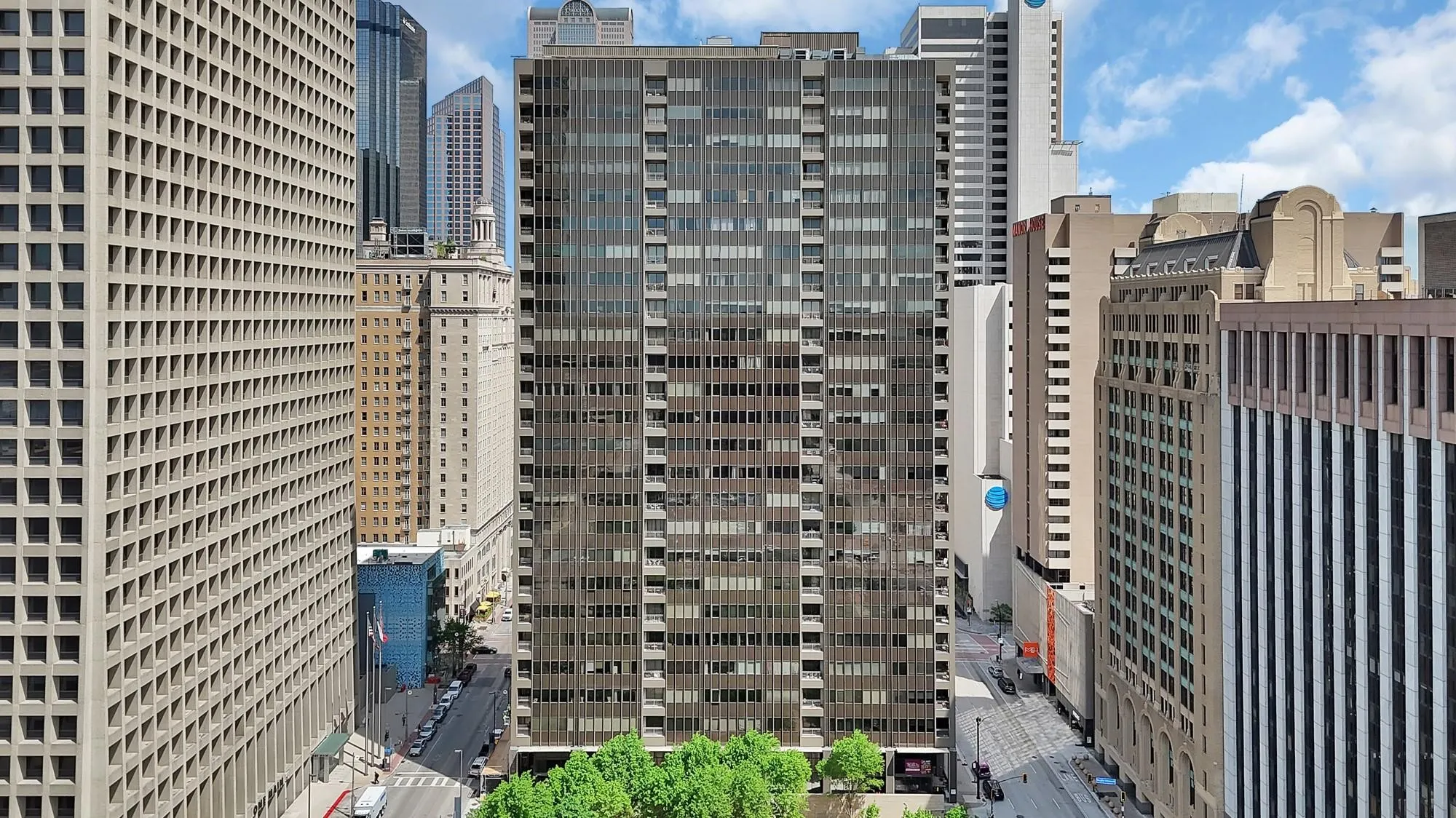 High-rise building with a dark facade and numerous windows, surrounded by a dense urban environment
