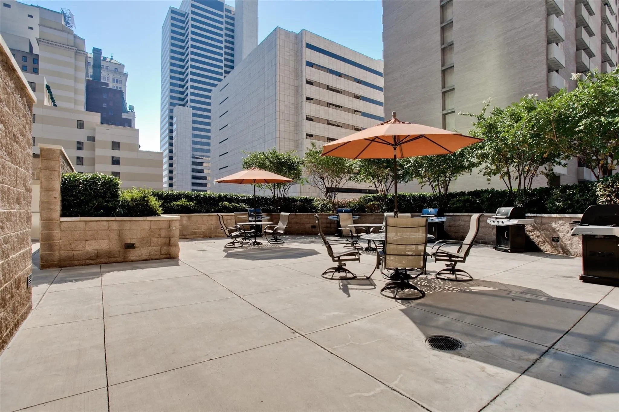 Expansive outdoor patio with concrete paving, stone planters, and integrated grilling stations