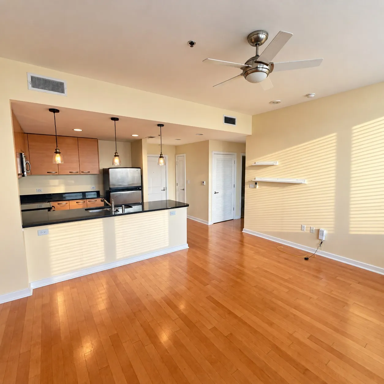 Wood-finish flooring throughout, kitchen with wood cabinetry, stainless steel appliances, and a dark countertop