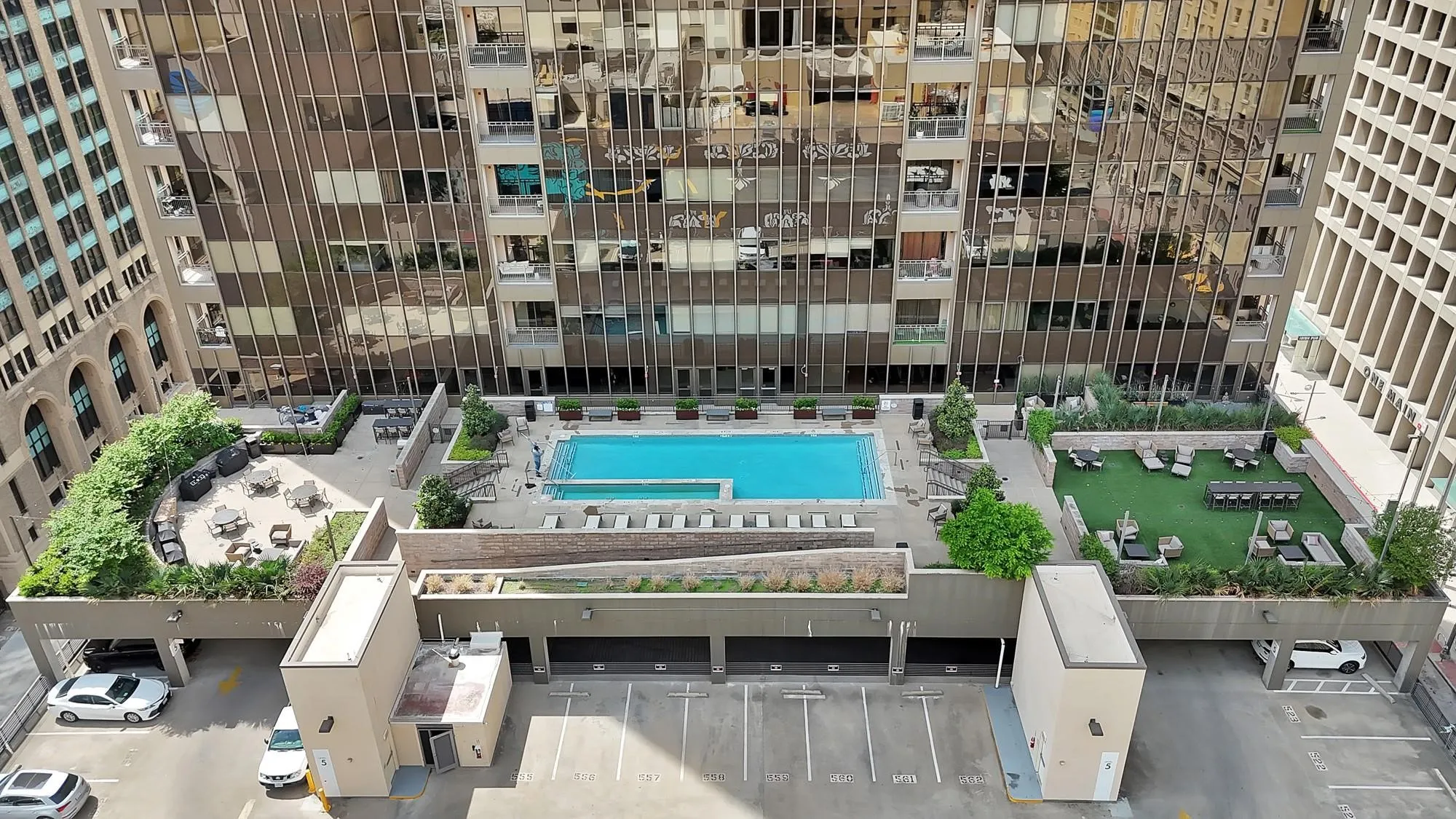 Rooftop amenity deck featuring a swimming pool, artificial turf lounge areas, landscaped planters, and paved patio spaces