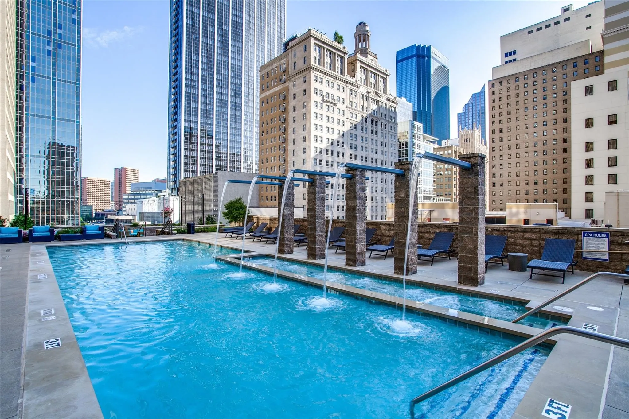 Expansive outdoor pool with integrated water features and surrounding stone-clad pillars, complemented by concrete decking