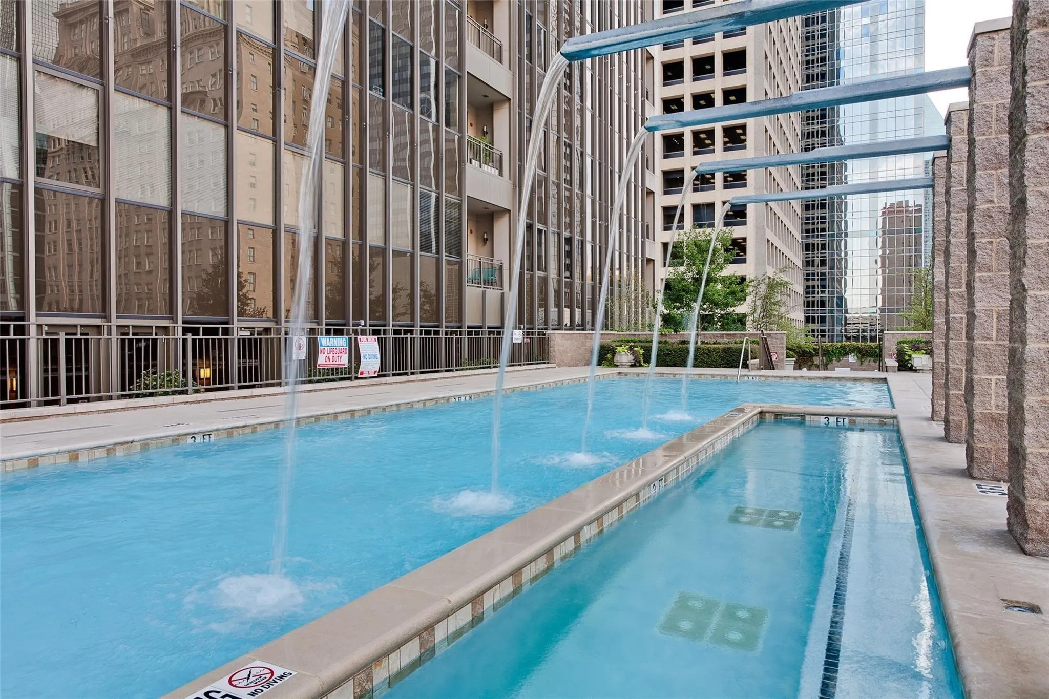 Elevated pool area featuring multiple water features, stone pillars, and an integrated water channel