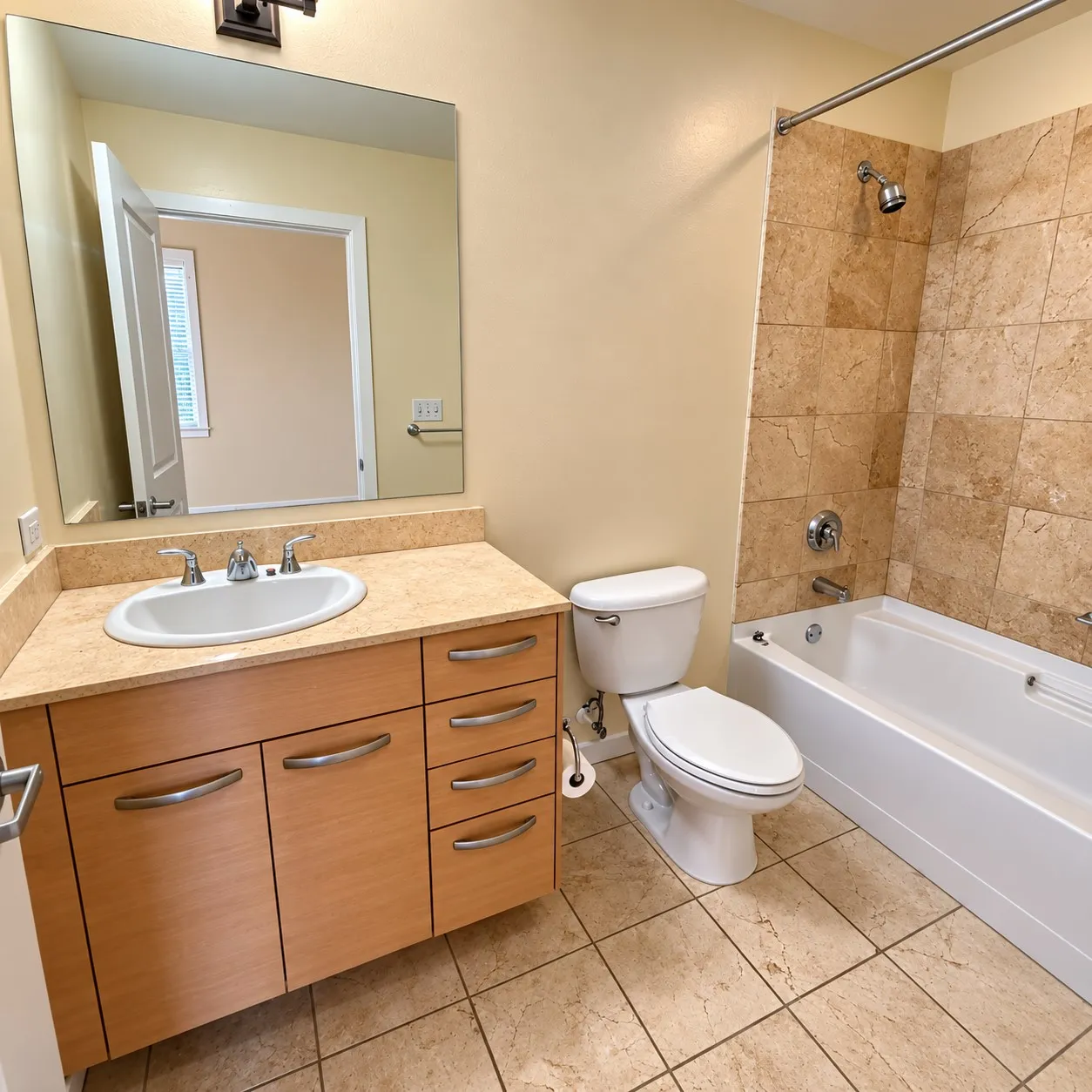 Bathroom featuring a wood-finish vanity with an integrated sink, stone-look countertop, a standard toilet, and a tiled shower-tub combination