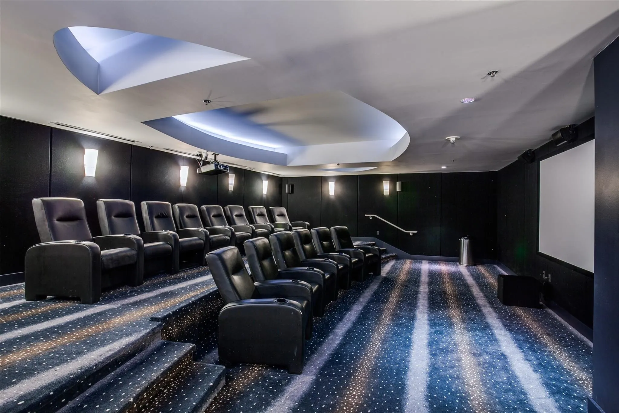 Tiered seating with individual recliners, a large projection screen, and integrated ceiling lighting