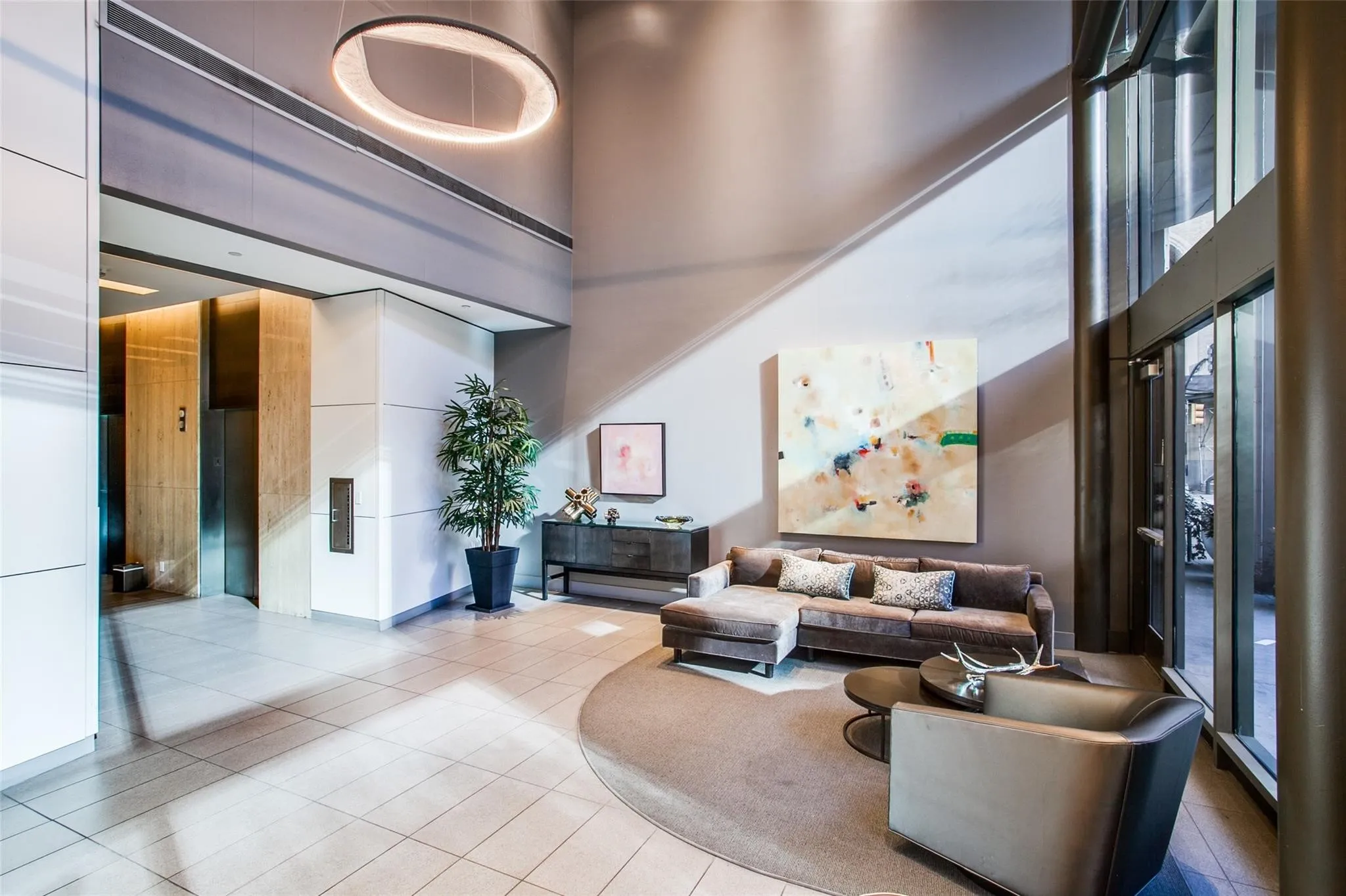 Two-story lobby featuring a circular chandelier, floor-to-ceiling windows, and tile flooring