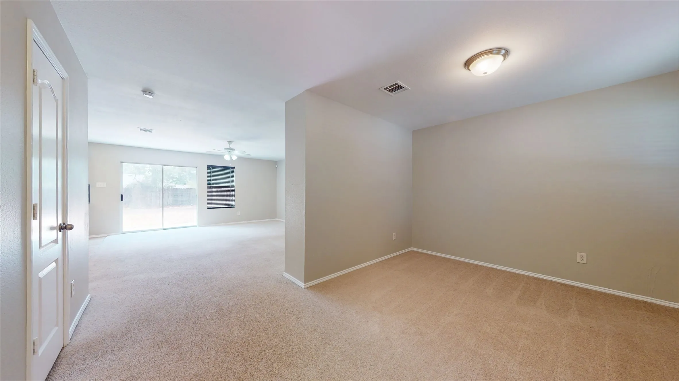 Neutral wall color, carpet flooring, ceiling-mounted light fixture, sliding glass door, ceiling fan