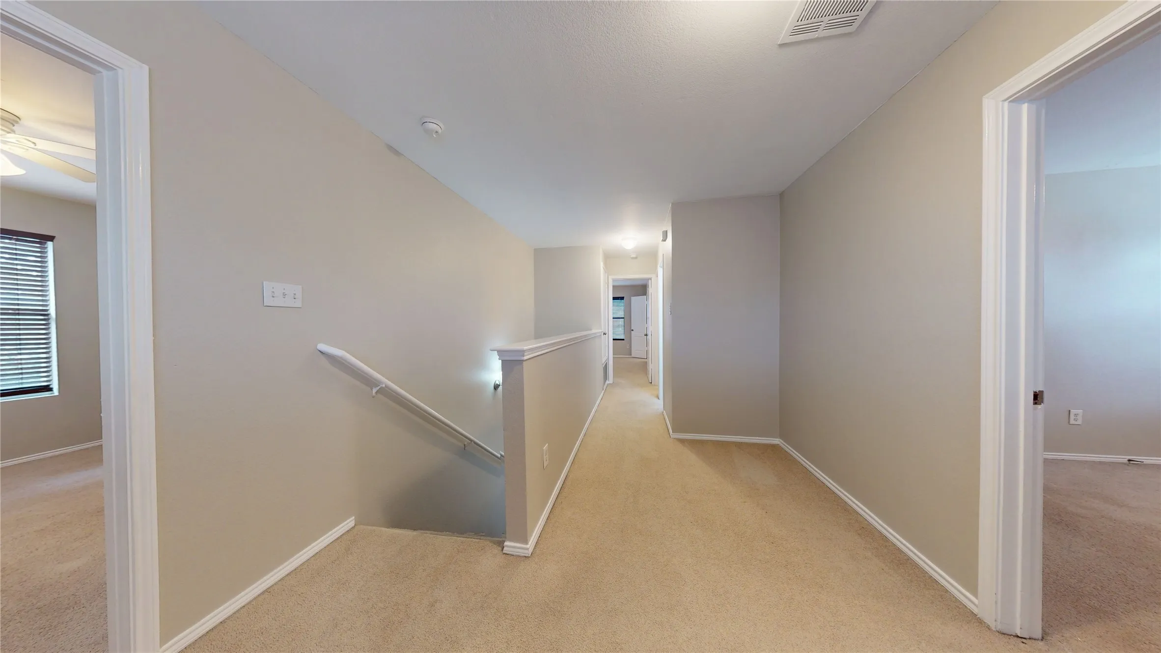 Carpeted hallway with neutral wall tones and white trim