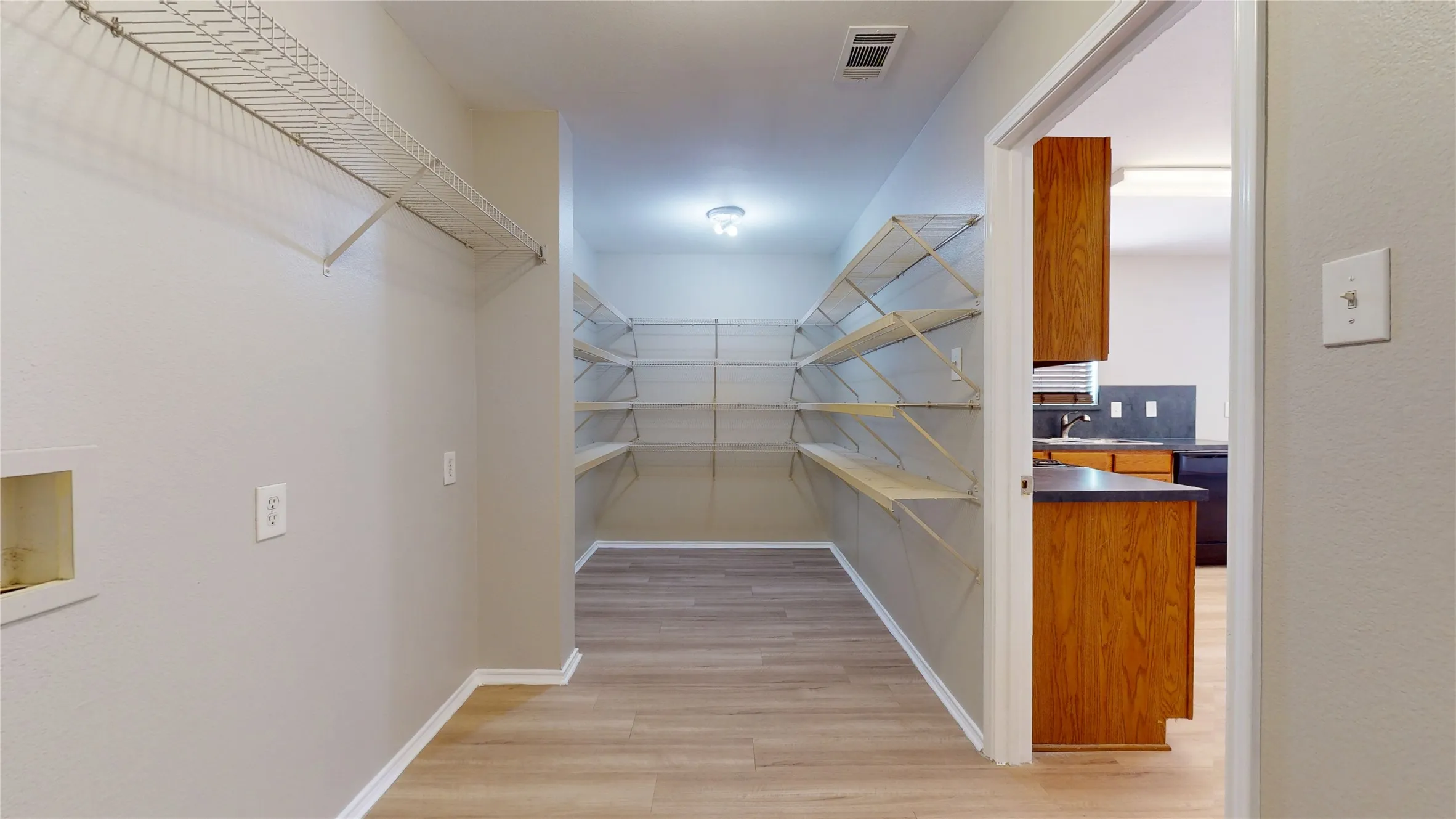 Laundry area with wire shelving and wood-finish flooring