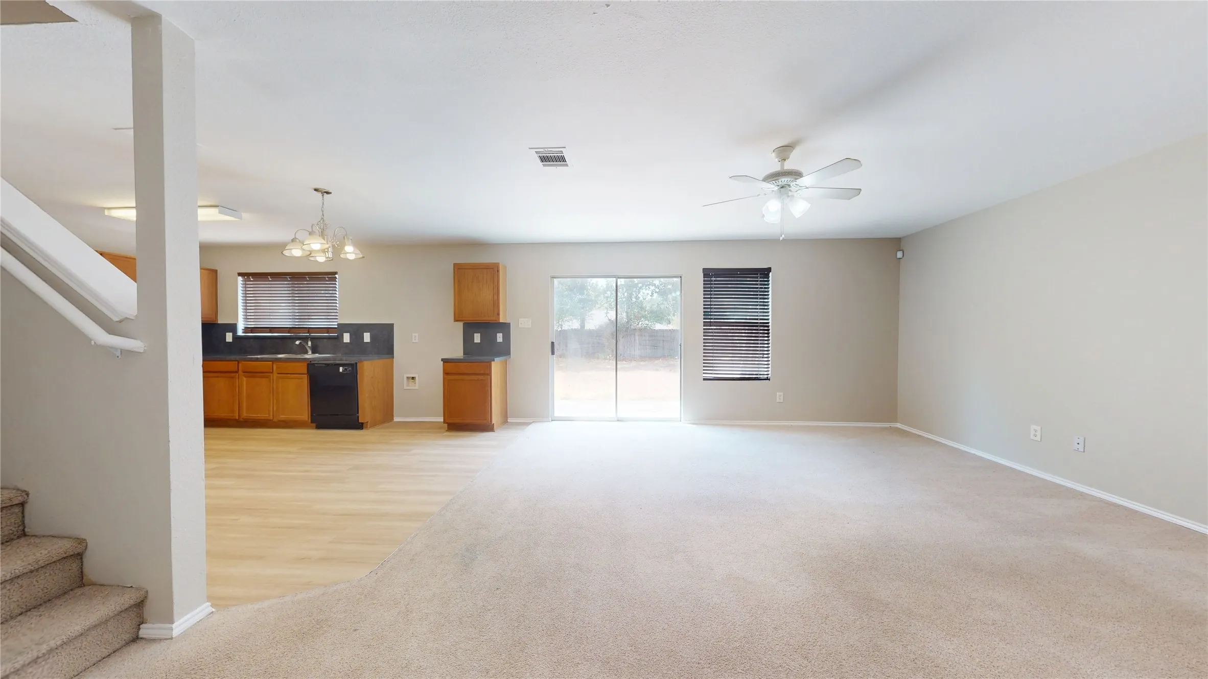 Open-concept living space featuring carpet flooring, ceiling fan, and sliding glass door