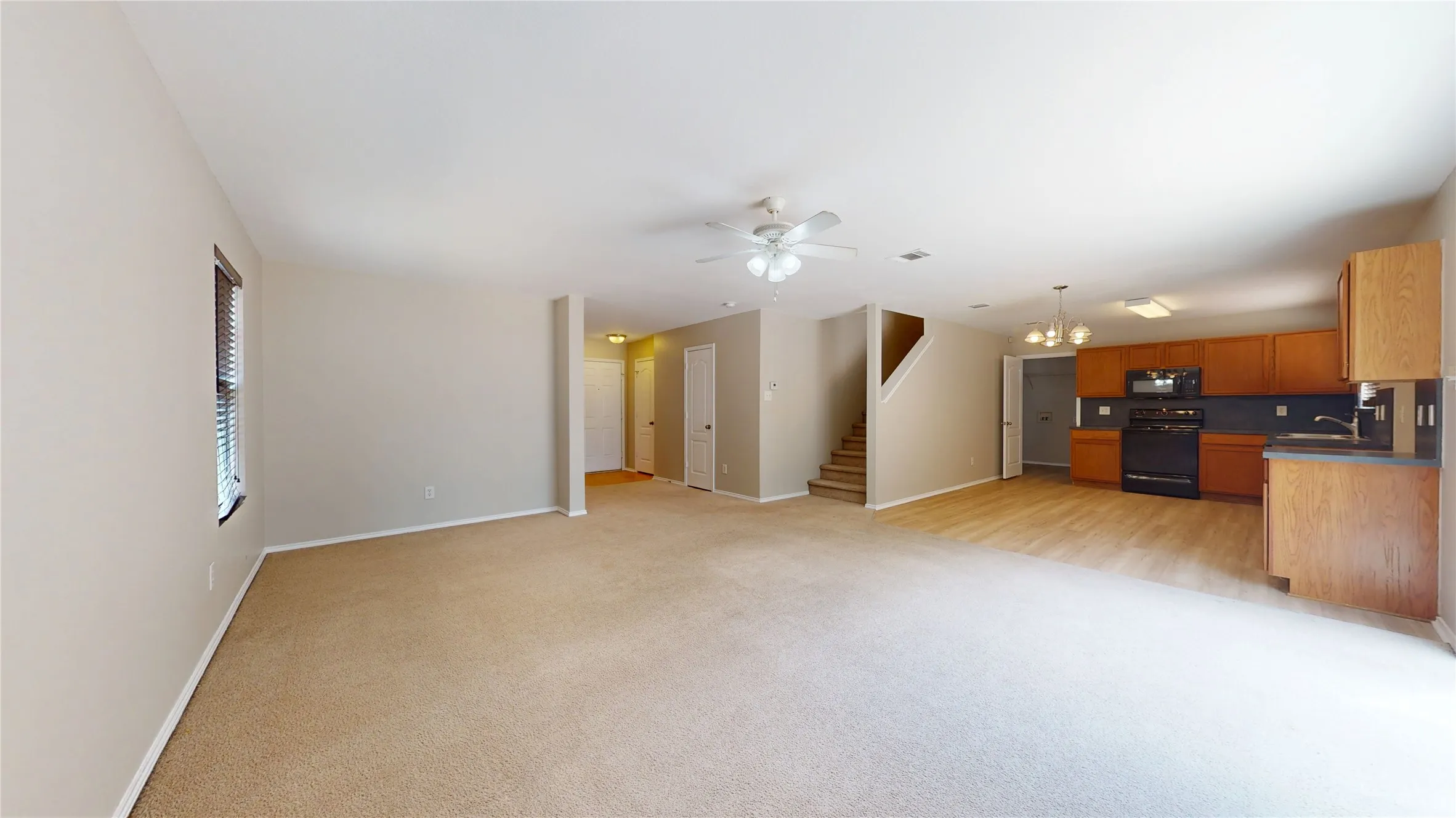 Expansive carpeted living space with a ceiling fan