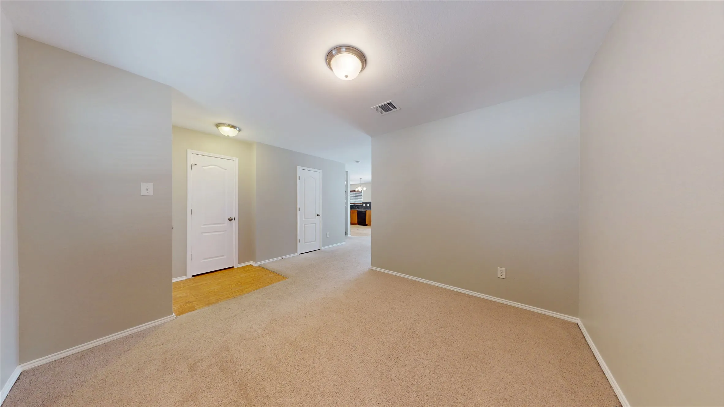 Neutral wall tones, carpeted flooring, wood-finish flooring in the entryway, and recessed lighting