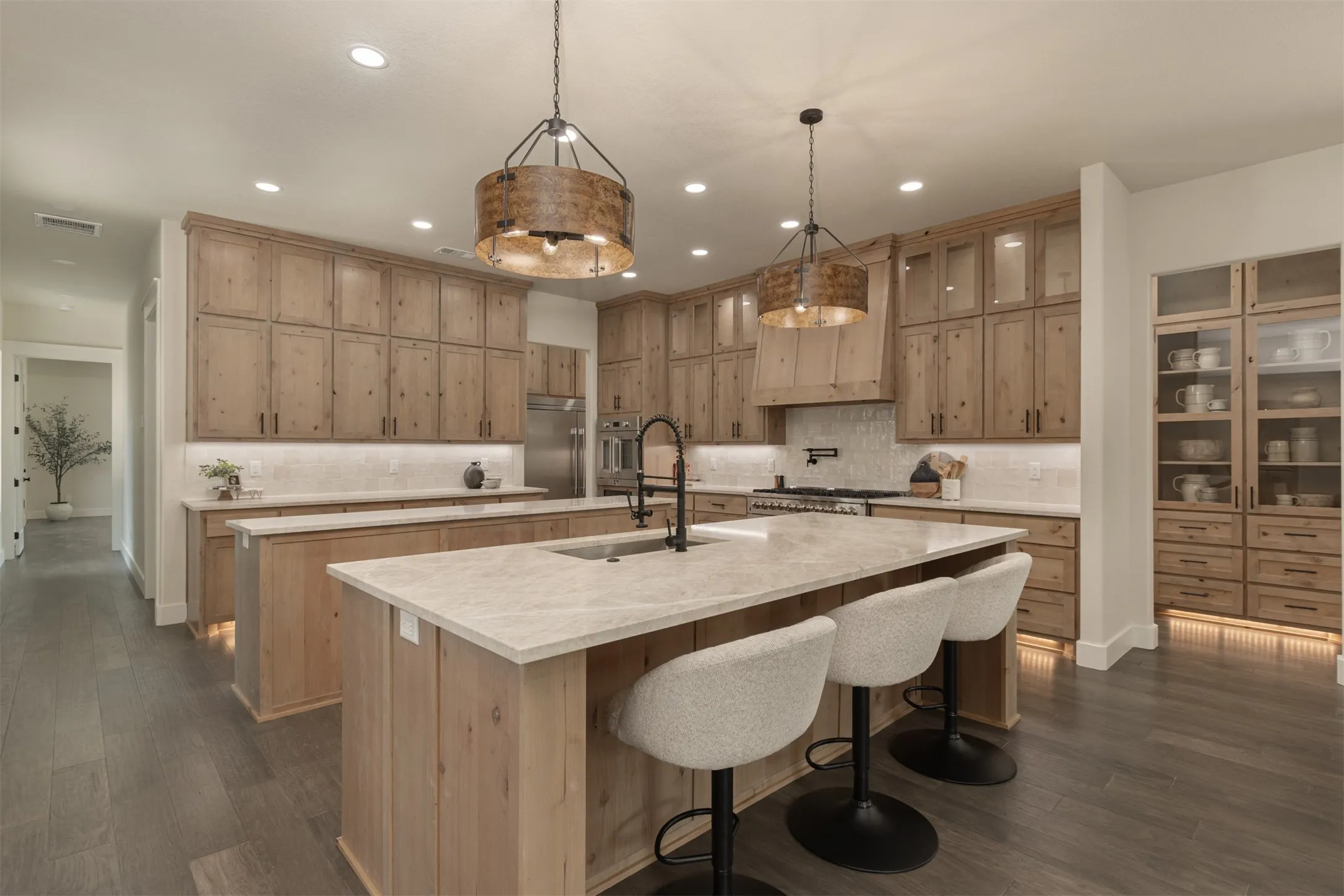 Kitchen featuring wood-finish cabinetry, two kitchen islands with stone countertops, and recessed lighting
