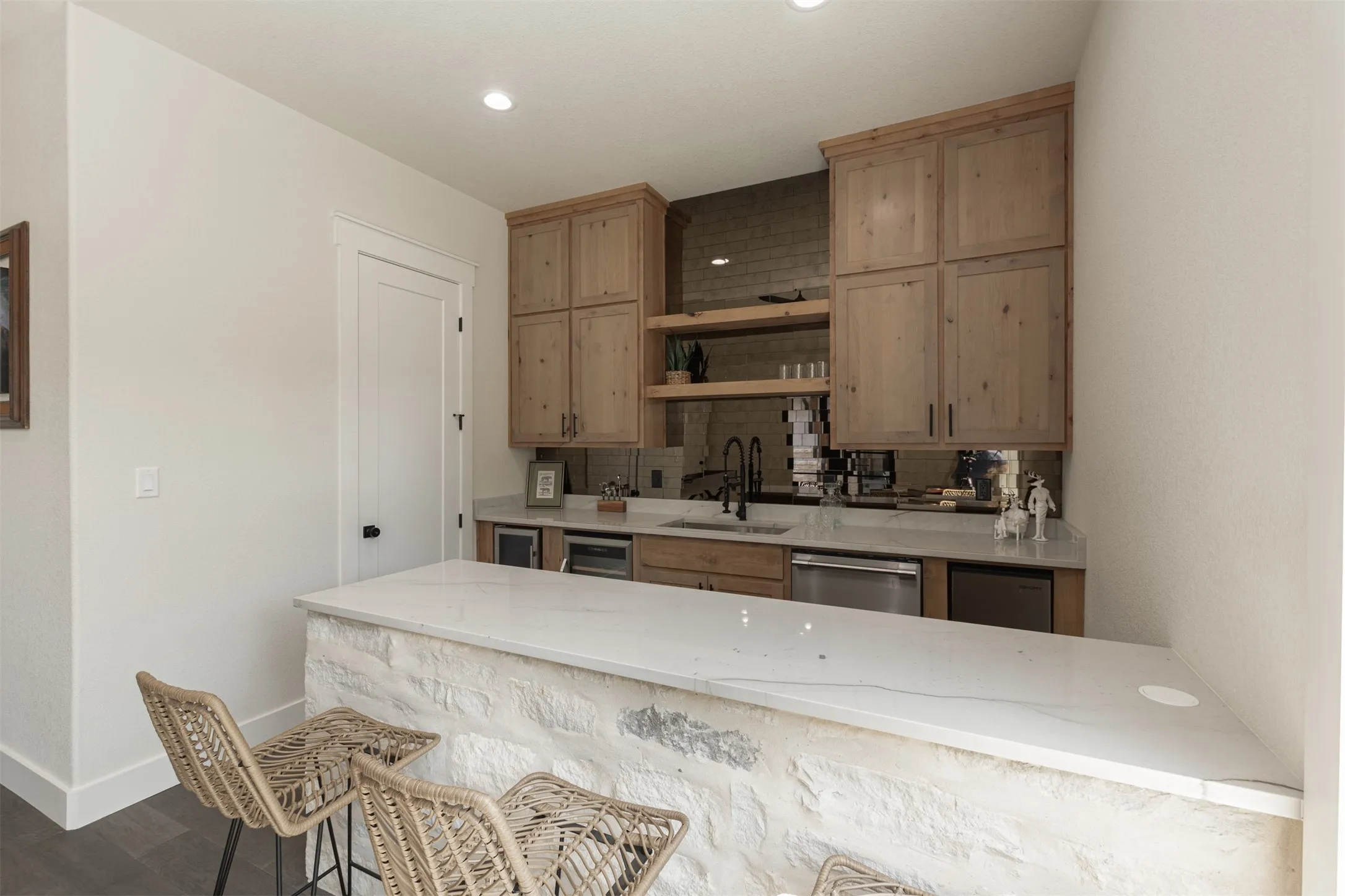 Stone-clad bar with a white countertop, wood cabinetry, built-in sink, and stainless steel appliances