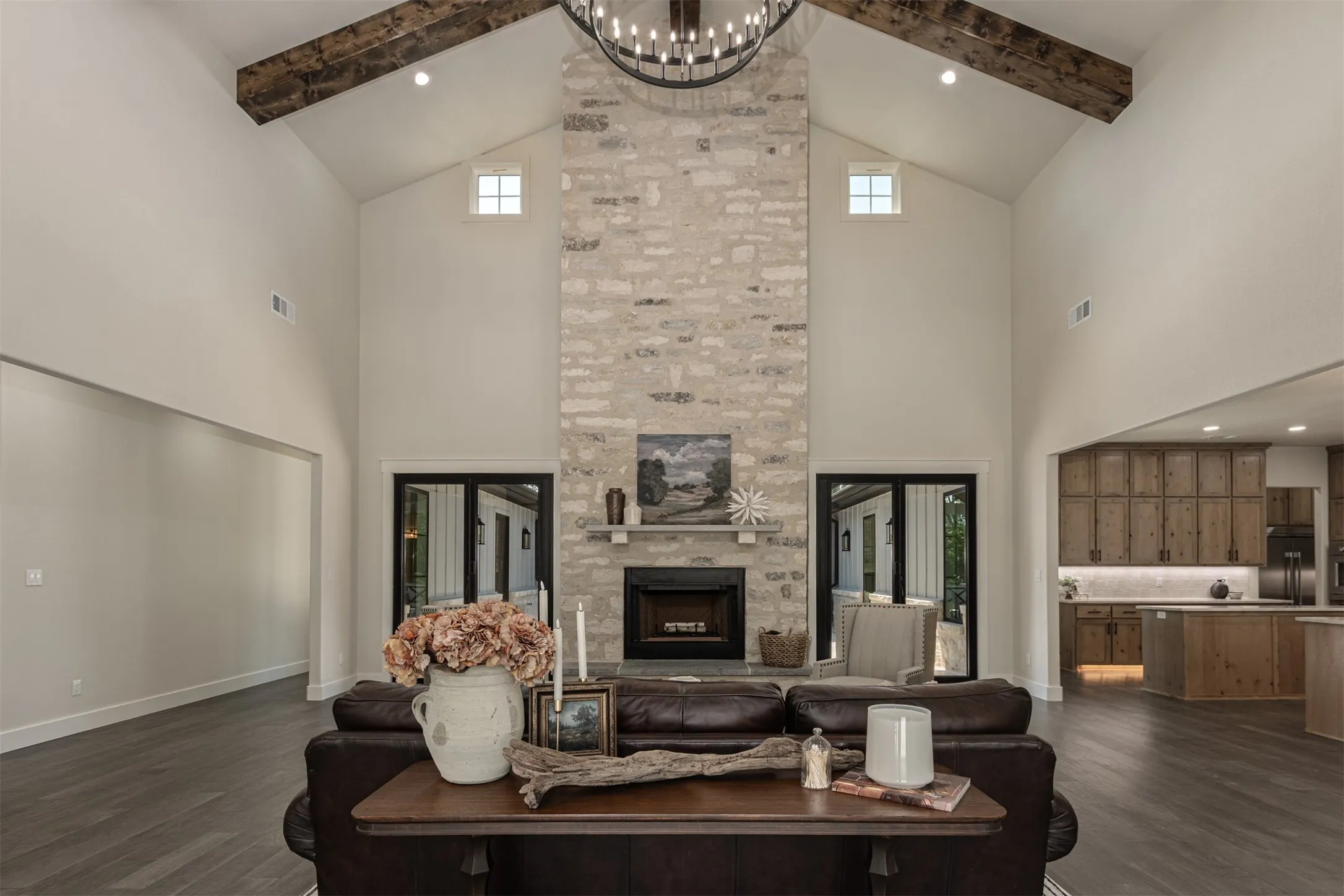 Vaulted ceiling with exposed wood beams, stone fireplace, and wood-finish flooring