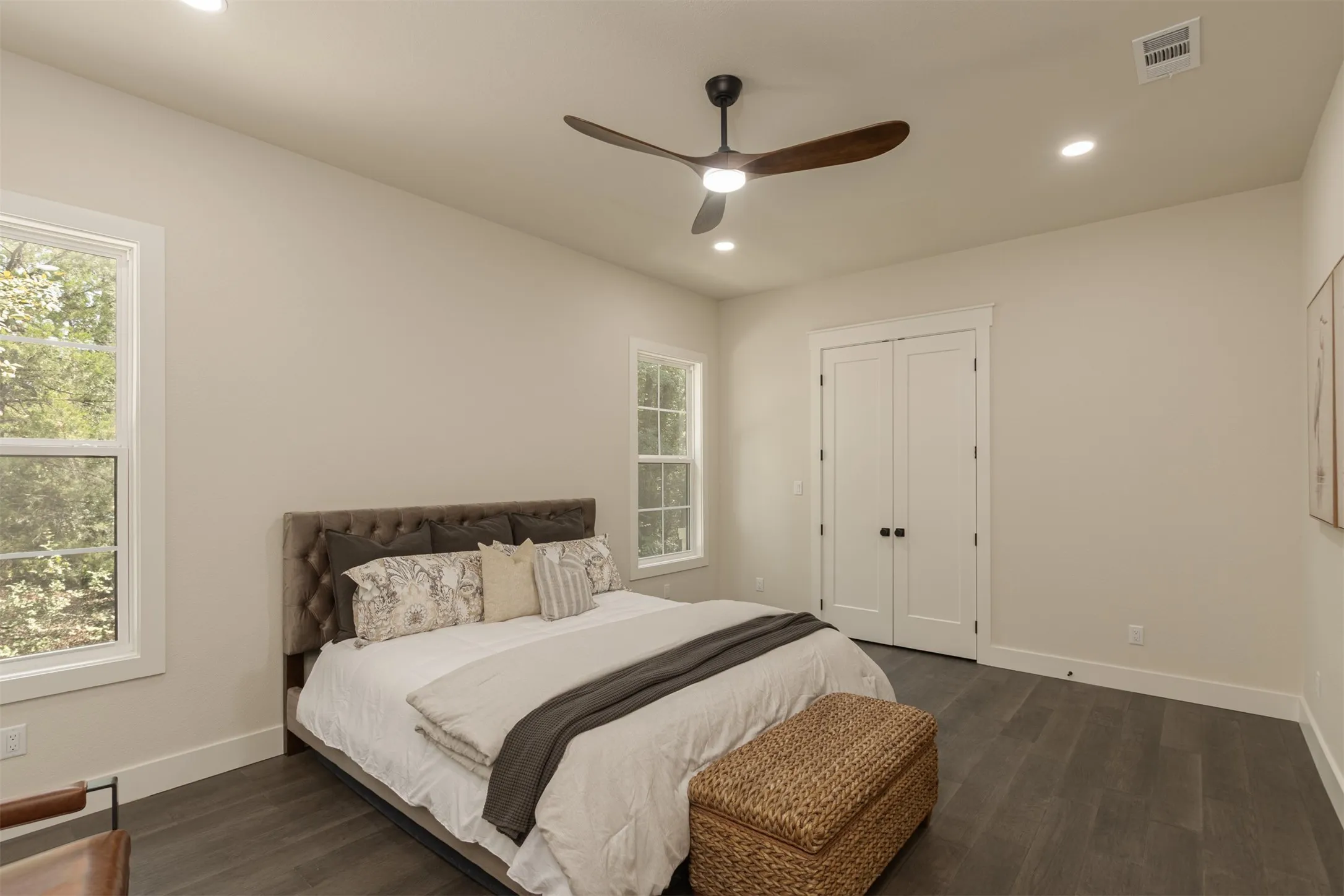 Wood-finish flooring, two large windows, white trim, recessed lighting, and a modern ceiling fan