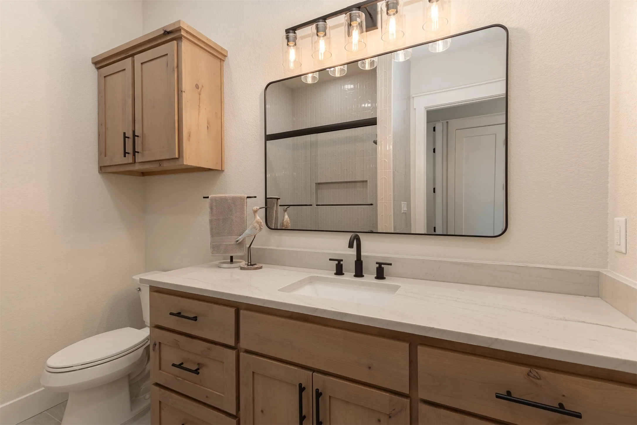 Spacious vanity with light-toned countertop, integrated sink, and matte black fixtures