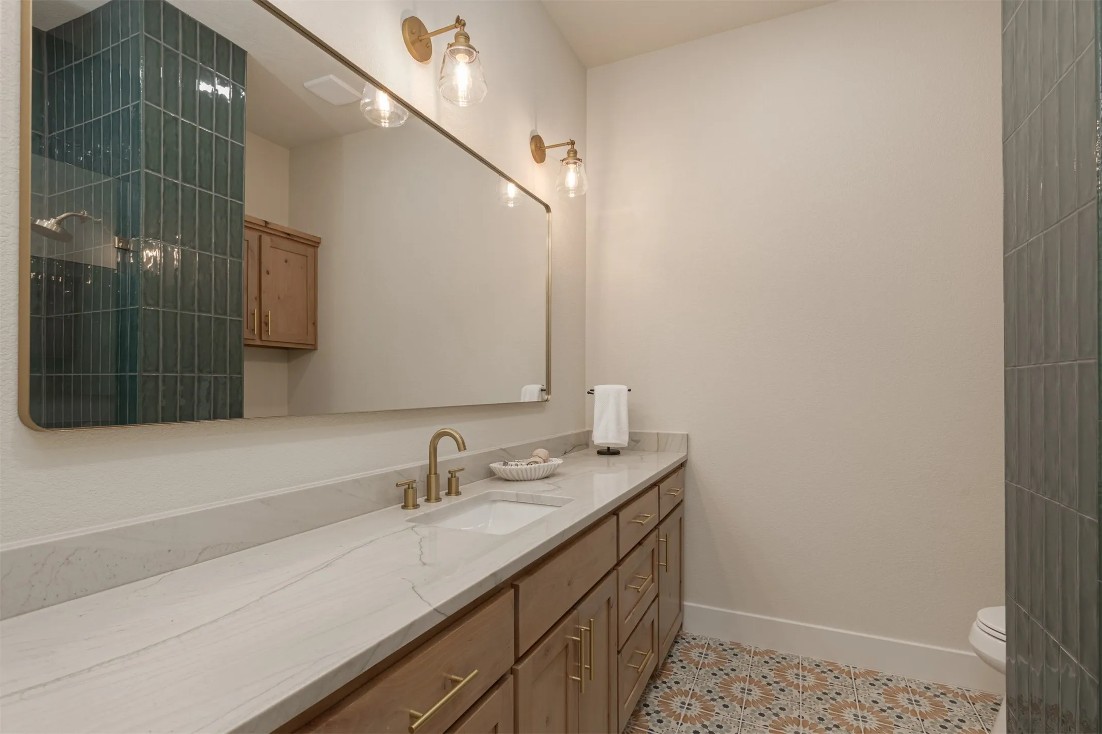 Extended vanity with an undermount sink, a light-toned countertop, and gold-finish fixtures