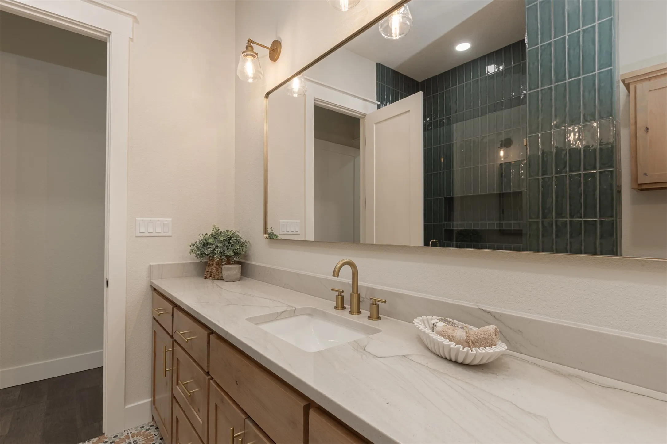 Dual-sink vanity with light-toned countertop, wood-finish cabinetry, and brass hardware