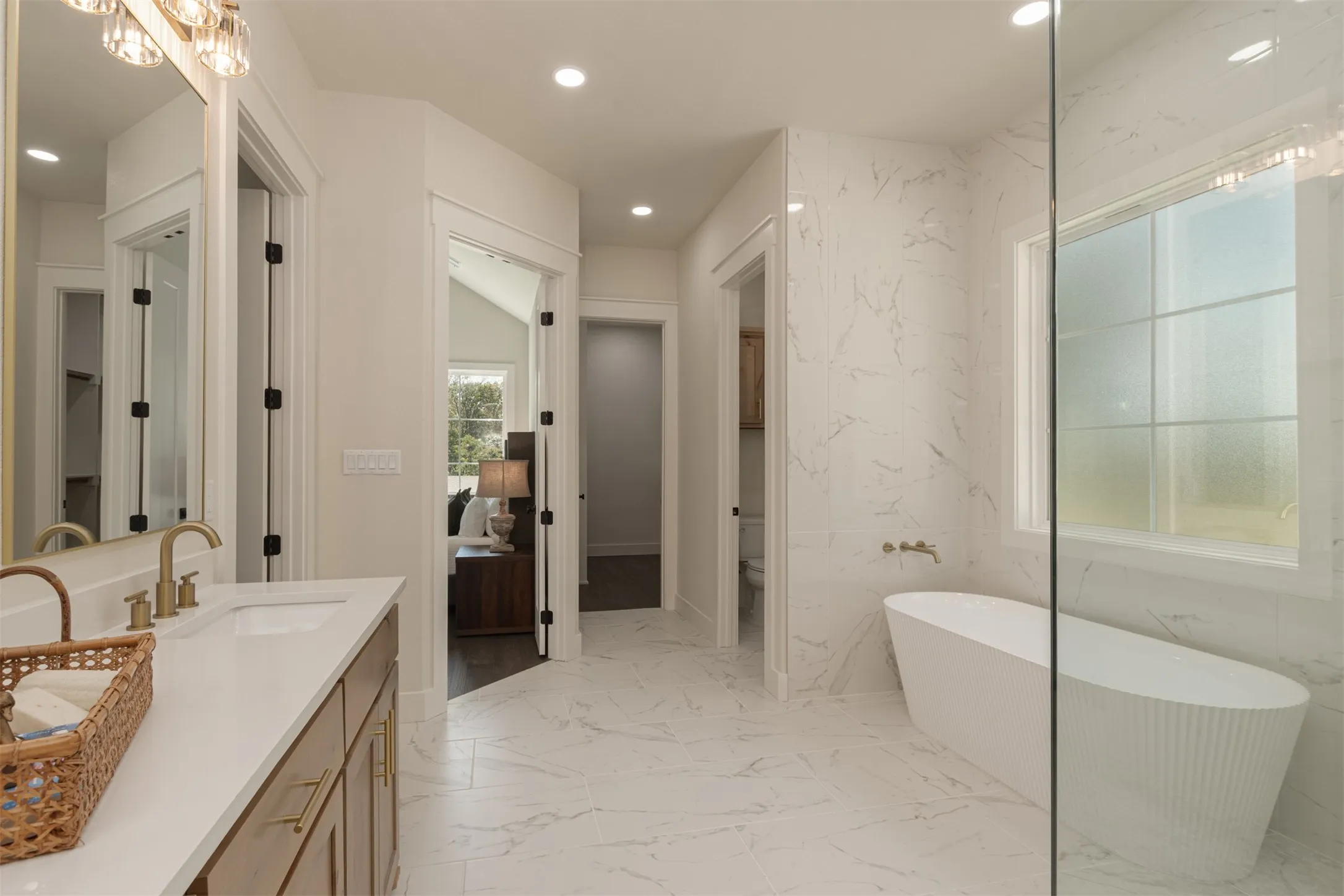 Spacious bathroom featuring a freestanding tub, glass-enclosed shower, dual vanity with undermount sinks, and large-format tile flooring