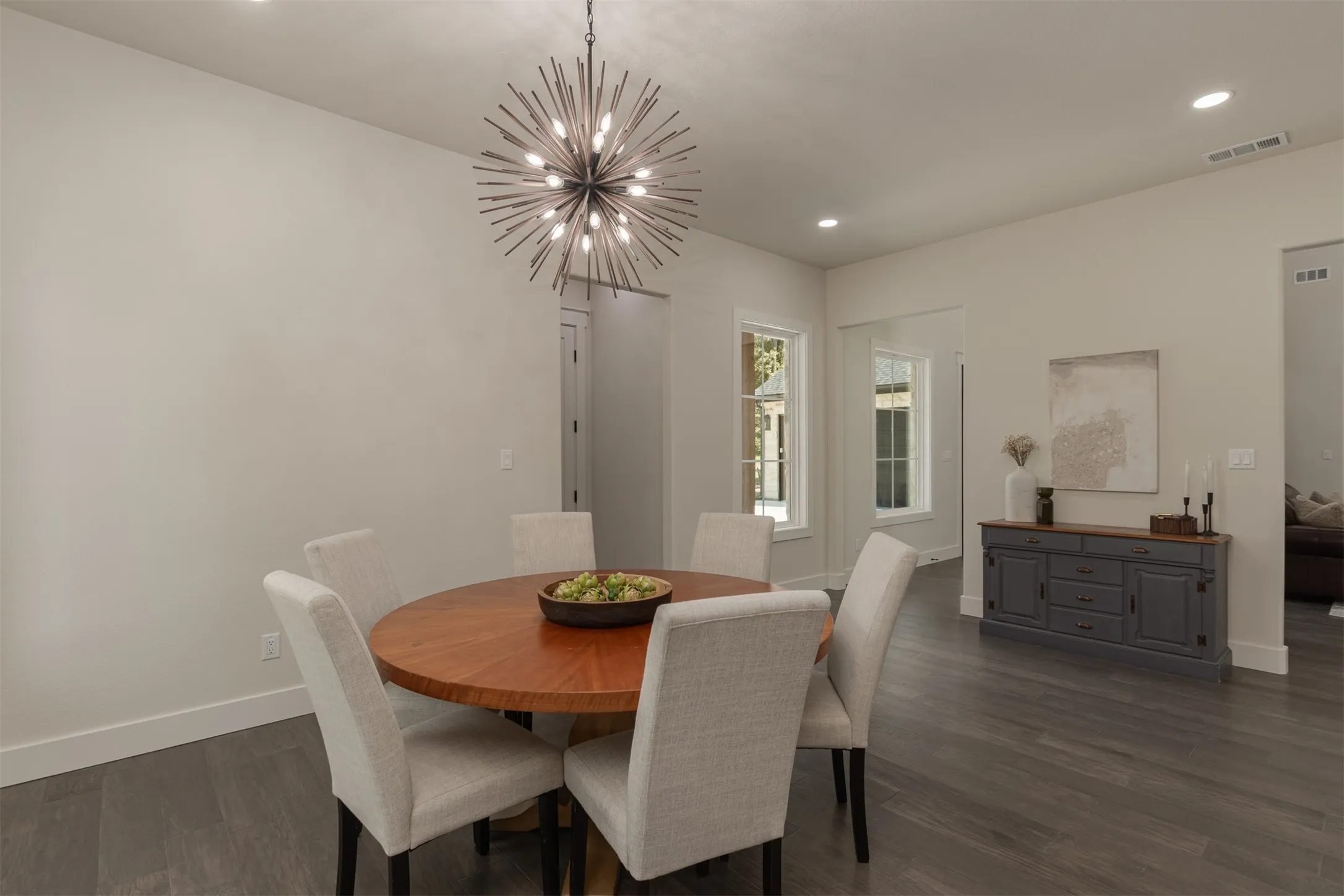 Wood-finish flooring throughout, featuring a modern sputnik chandelier, recessed lighting, and a built-in buffet