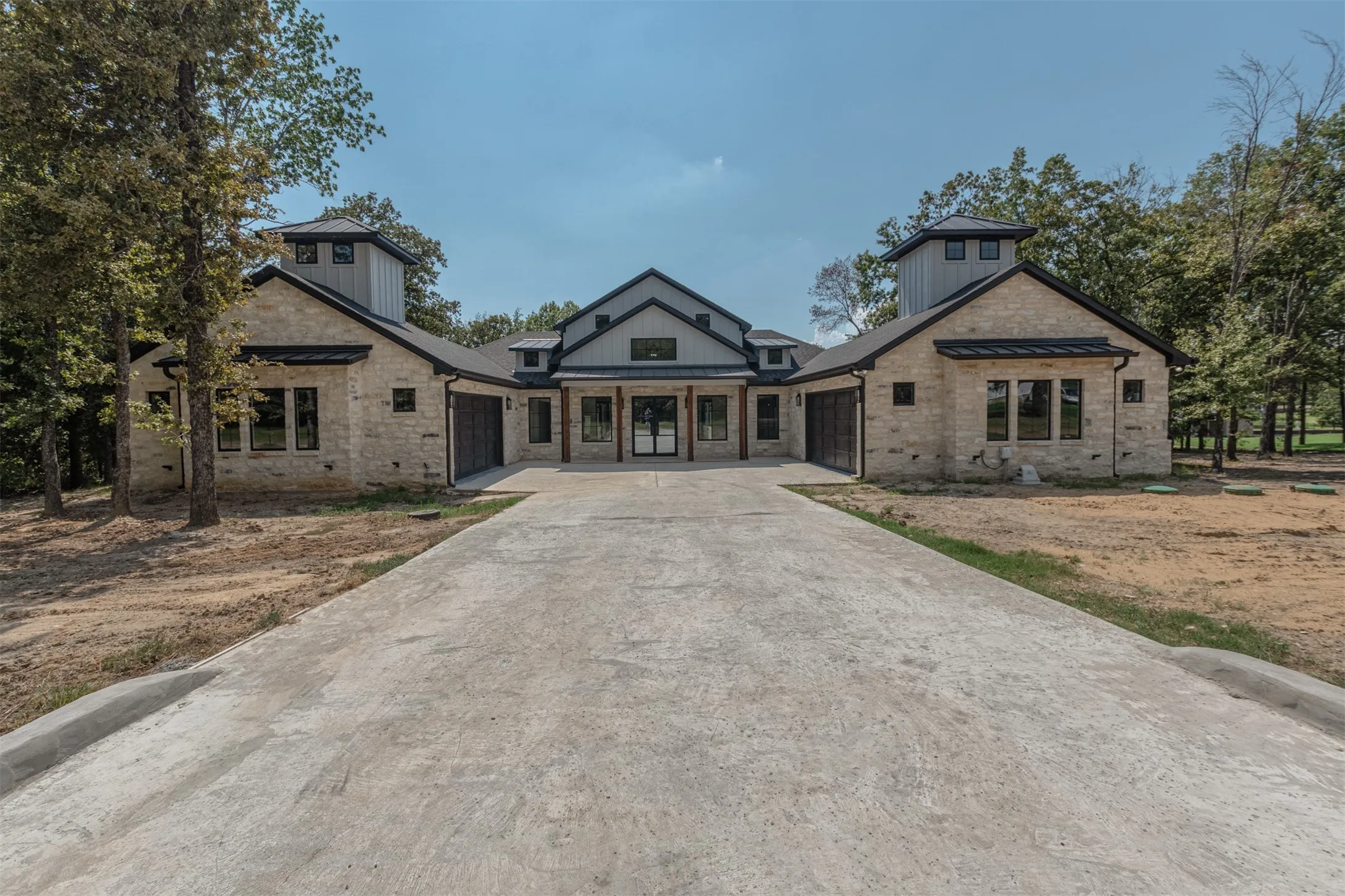 Stone exterior with black-framed windows, a concrete driveway, and a gabled roofline