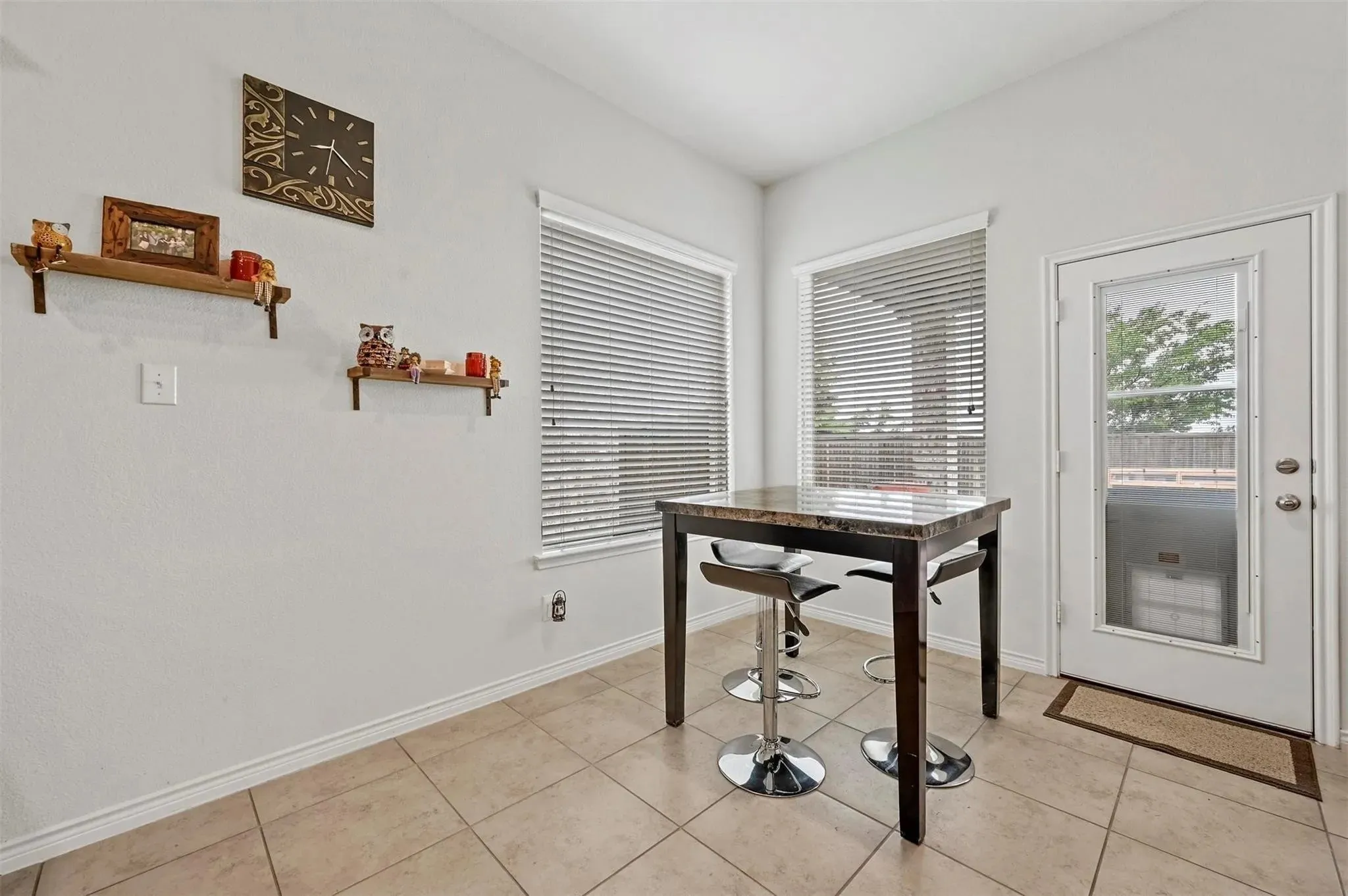 Tile flooring, built-in shelving, multiple windows with blinds, and a glass-paneled exterior door