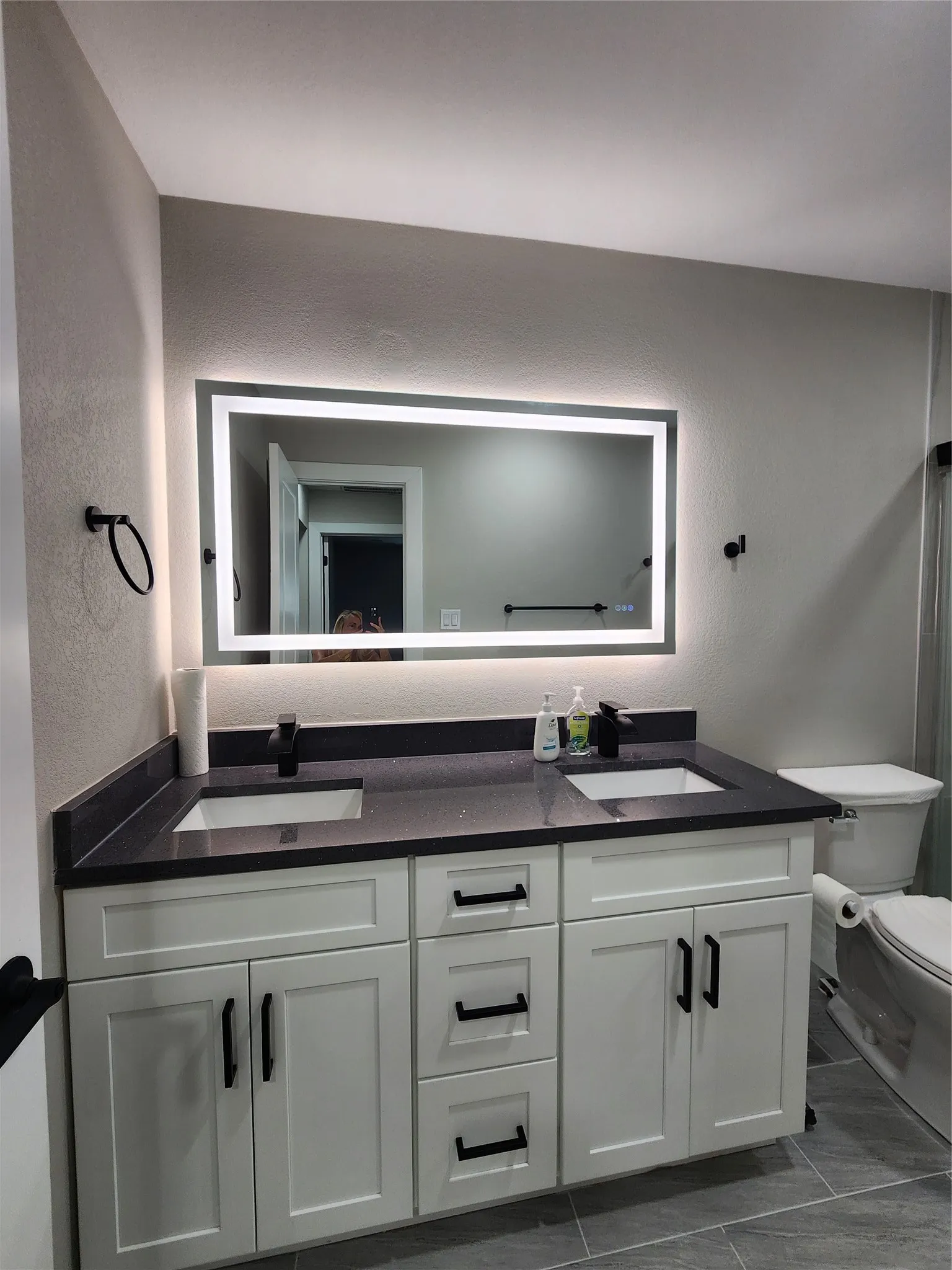 Double vanity with white cabinetry, dark countertops, undermount sinks, and matte black hardware