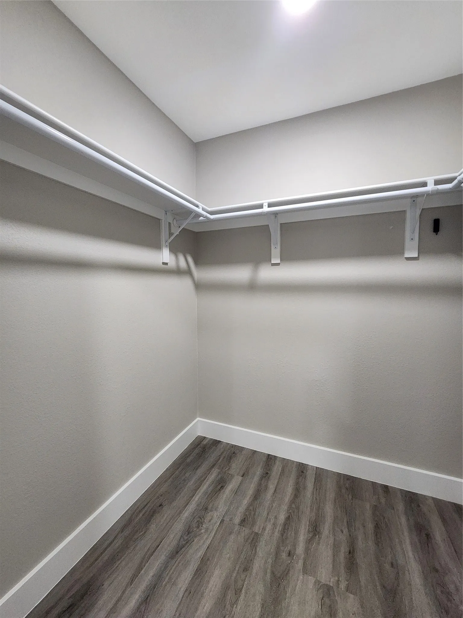 Corner storage with wood-finish flooring, white shelving, and ceiling-mounted lighting