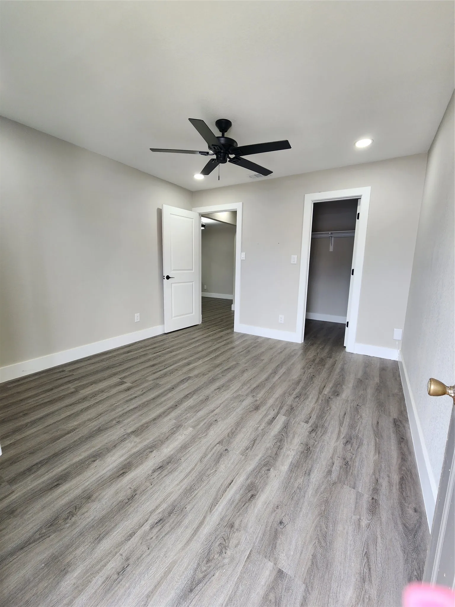 Wood-finish flooring, recessed lighting, and a matte black ceiling fan