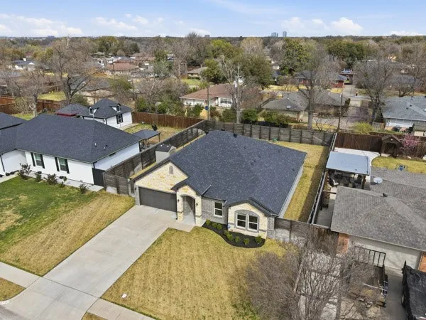 Stone and siding exterior with a two-car garage, mature landscaping, and a fenced backyard