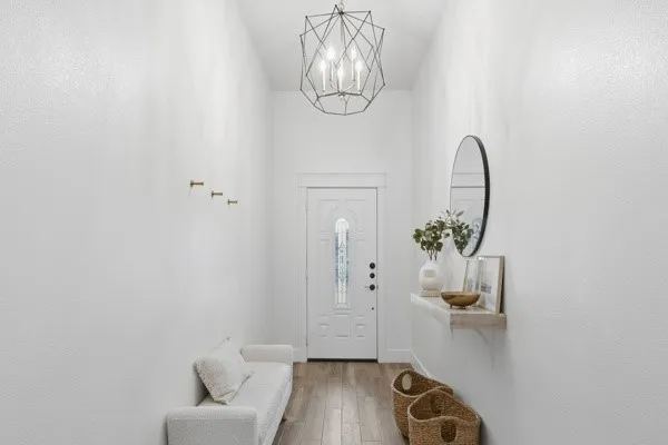 Entryway featuring wood-finish flooring, a decorative front door with transom window, and a geometric pendant light fixture