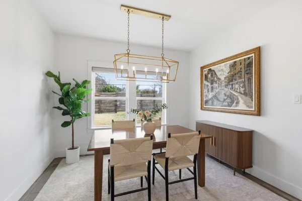Dining area featuring a gold-tone geometric chandelier, wood-finish flooring, and a large window