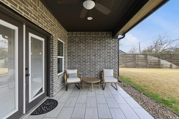 Covered patio featuring wood-finish tile flooring, a ceiling fan, and a brick exterior