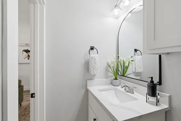 White vanity with a single basin sink, silver-tone faucet, and stone-finish countertop