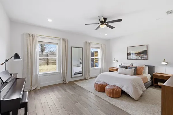 Spacious room featuring light wood-finish flooring, recessed lighting, a ceiling fan, and multiple windows
