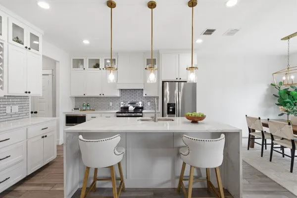 Contemporary kitchen featuring white cabinetry, a large kitchen island with a waterfall countertop, stainless steel appliances, and a tiled backsplash