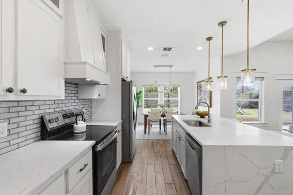 Gourmet kitchen with white shaker cabinetry, stone countertops, subway tile backsplash, and stainless steel appliances